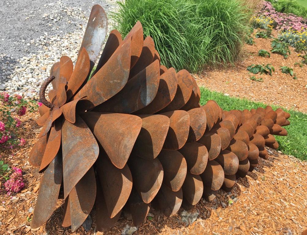 Through a consideration of the pine cone as a colonization device, Elzinga explores the nature of seeds and highlights their aggressive regeneration. This long, sleek pine cone is made from a steel that naturally rusts, producing an orange-brown