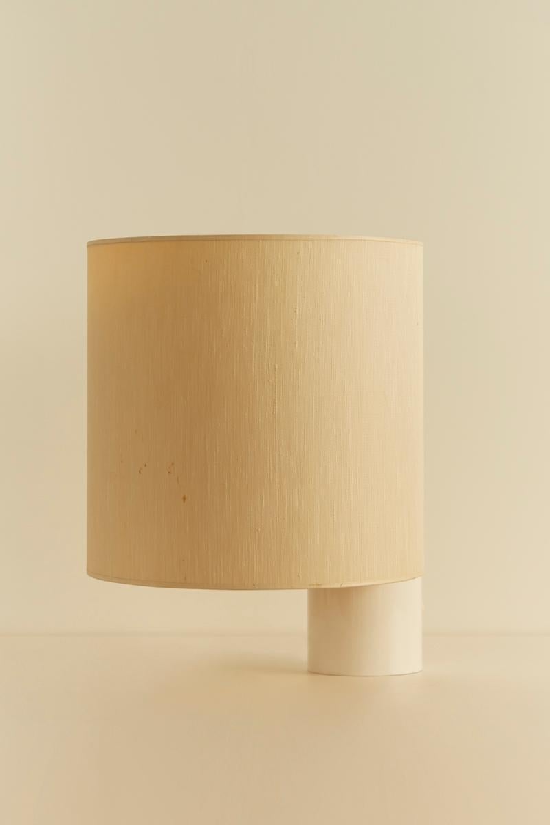 A large version of the Fluette table lamp, designed by Giuliana Gramigna for Quattrifolio in the 1970s, features a cylindrical white enameled aluminum frame paired with a cylindrical plasticized fabric lampshade.