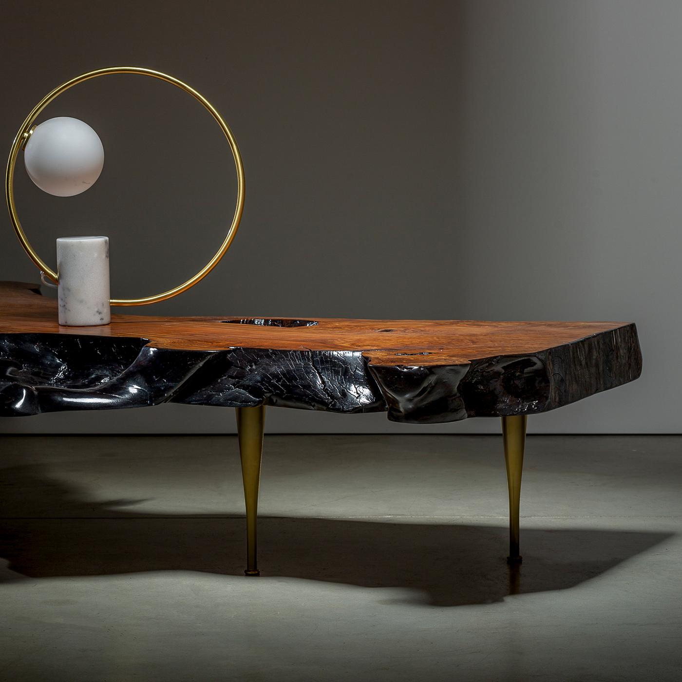 A thick and sinuous tabletop from a century-old olive stump is the outstanding element of this one-of-a-kind coffee table. Resting on a glamorous base of stiletto brass legs, it seduces with its irregular, dyed-black profiles shaped by nature and