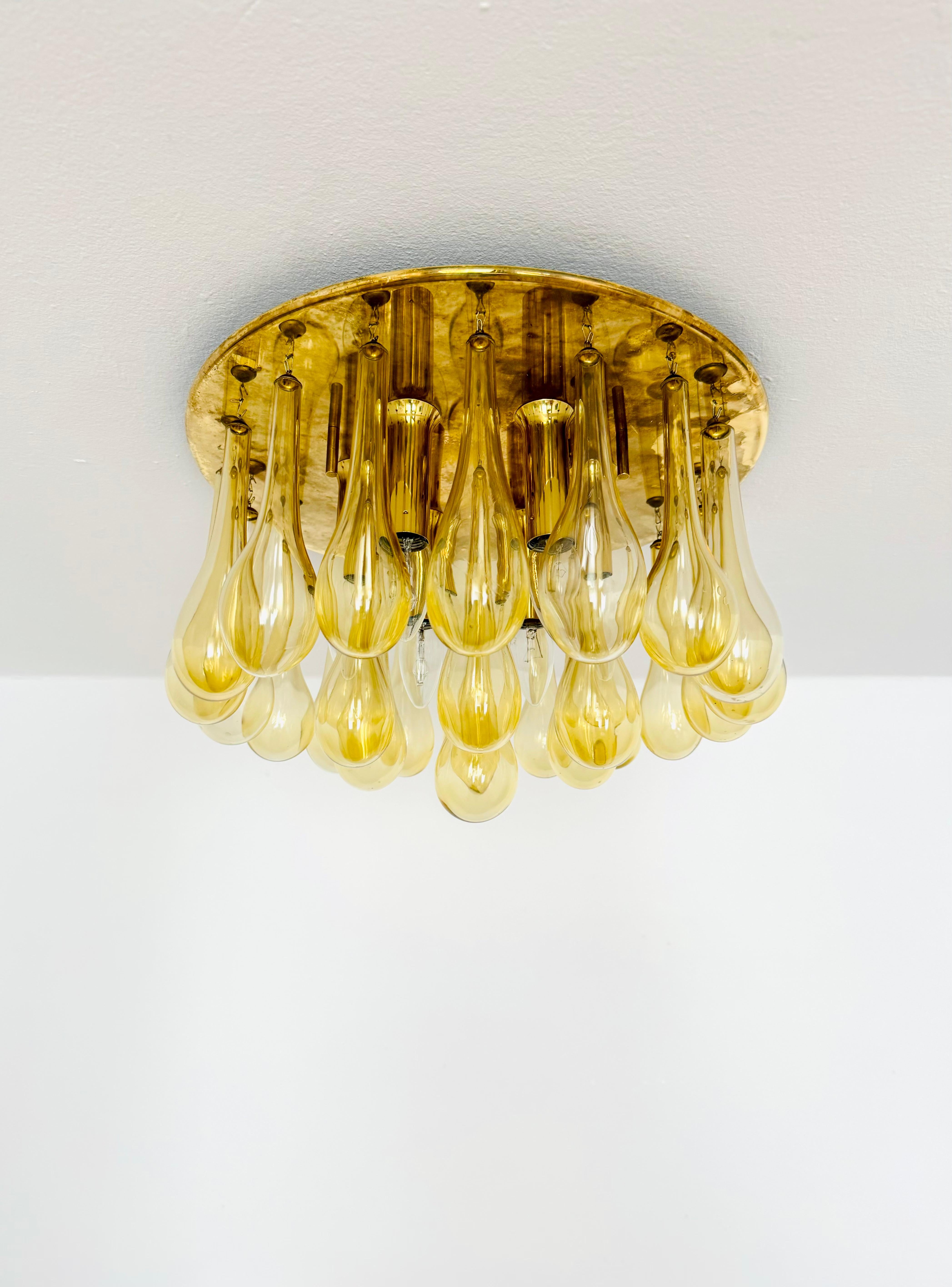 Imposant plafonnier en verre des années 1960.
Une conception exceptionnellement réussie et une très grande qualité de traitement.
Les 25 grands cristaux diffusent un jeu de lumière spectaculaire dans la pièce.
Très luxueux et un enrichissement pour