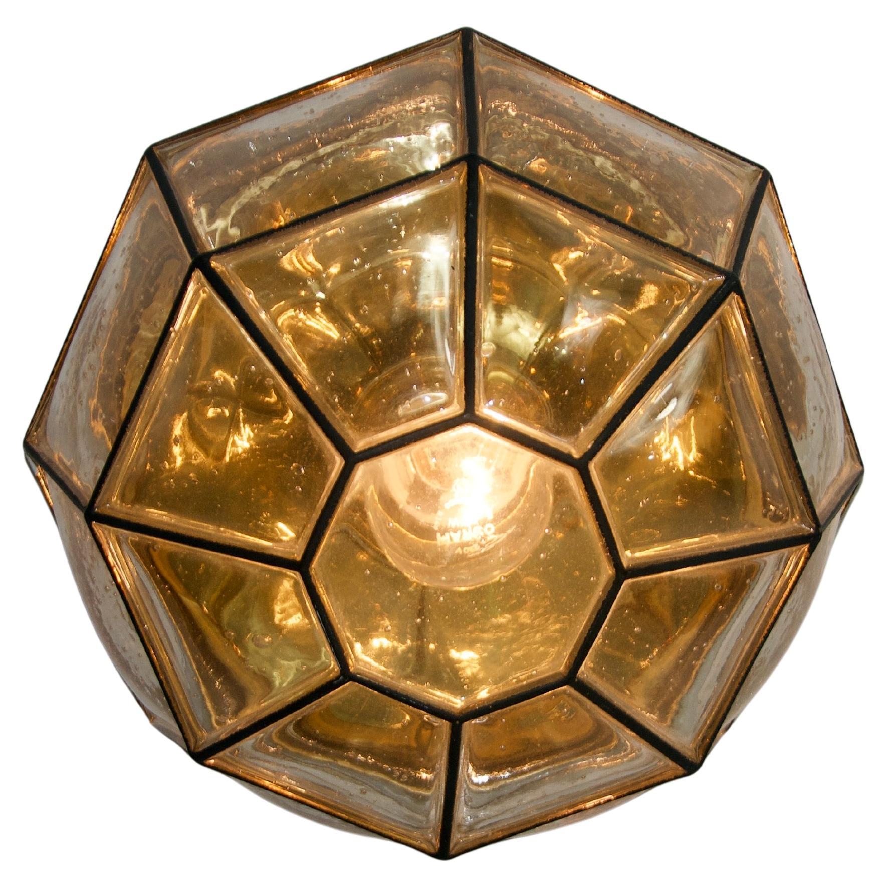 This exquisite brass ceiling lamp by Limburg from the 1960s embodies timeless elegance and high-quality craftsmanship. Its geometric design, featuring structured glass panels with a warm, golden hue, creates a sophisticated play of light and shadow.