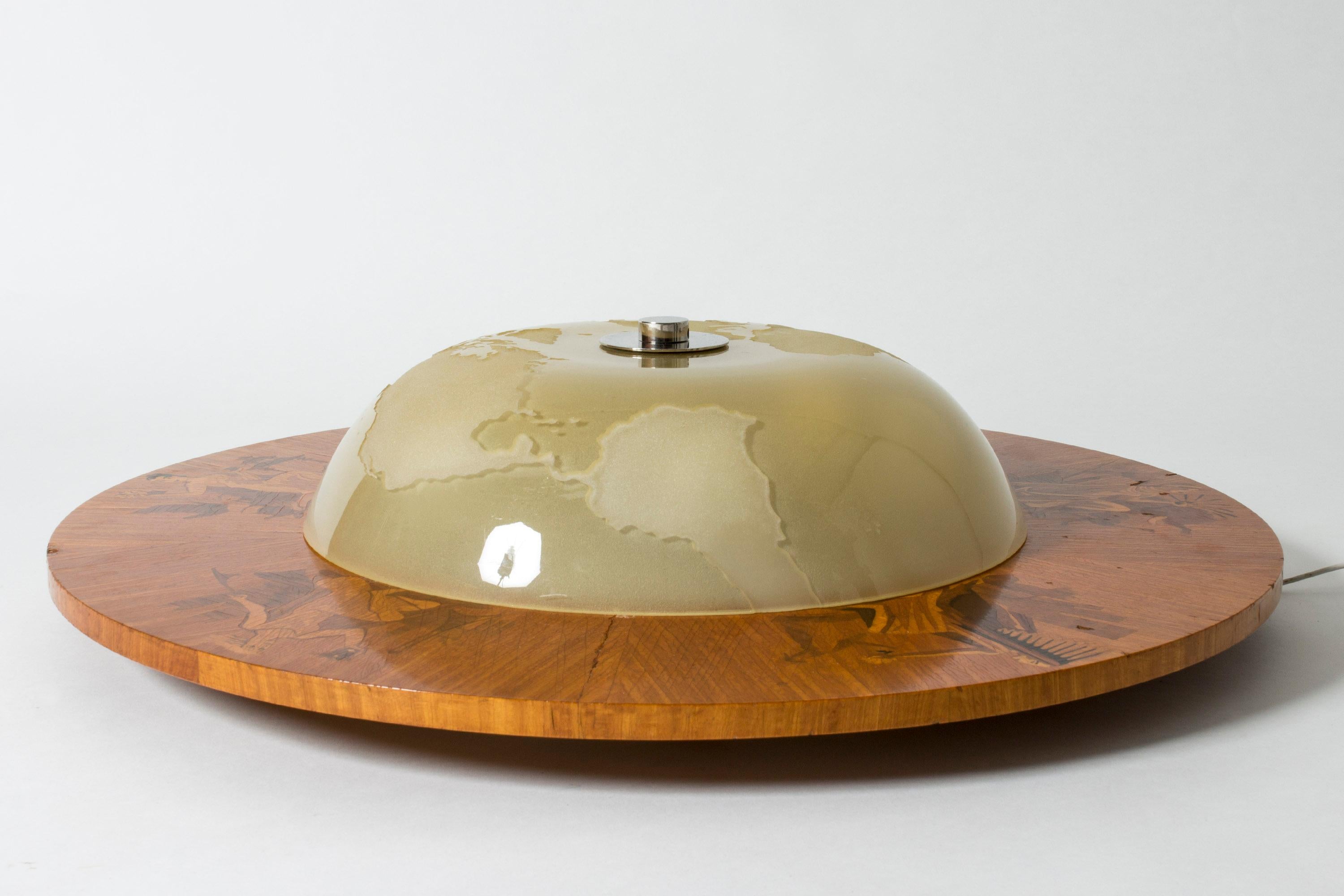 Striking, large 1930s flush mount ceiling light by Birger Ekman. Rare design with a round glass shade with decor of a world map. Wide wooden frame with beautiful inlays of women in traditional clothes, representing different areas of the world.