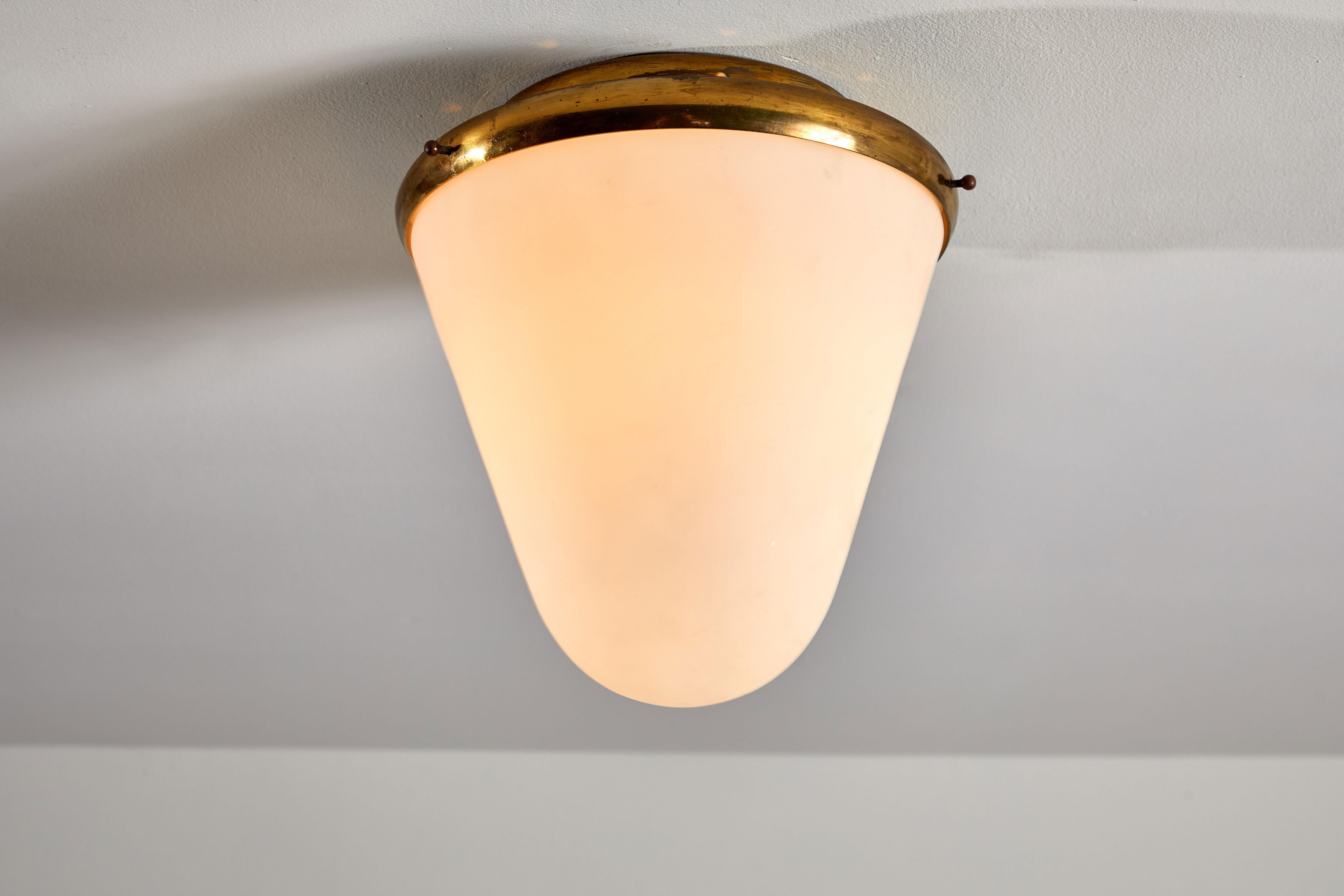 Flush mount ceiling light by Stilnovo. Manufactured in Italy, circa 1950s. Brushed satin glass diffuser, brass base and hardware. Rewired for US junction boxes. 
Takes one E27 Edison bulb, 40 watts maximum. Bulb provided as a one time courtesy.