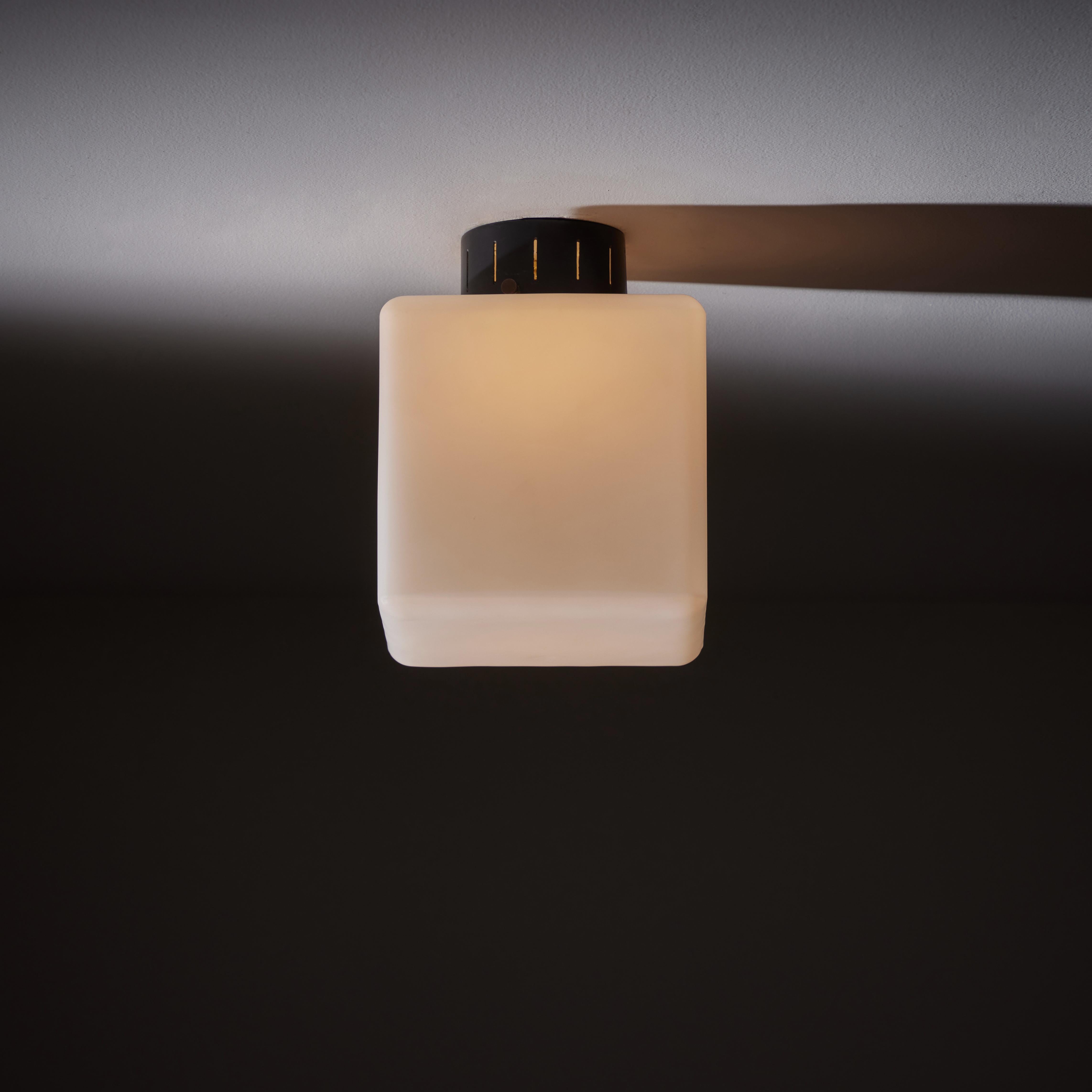 Flush mount ceiling lights by Stilnovo. Designed and manufactured in Italy, circa the 1960s. Simple, cubic milk glass shades offering ambient light diffusion; mounted to the ceiling with a black enameled canopy. We recommend one E27 40w maximum bulb