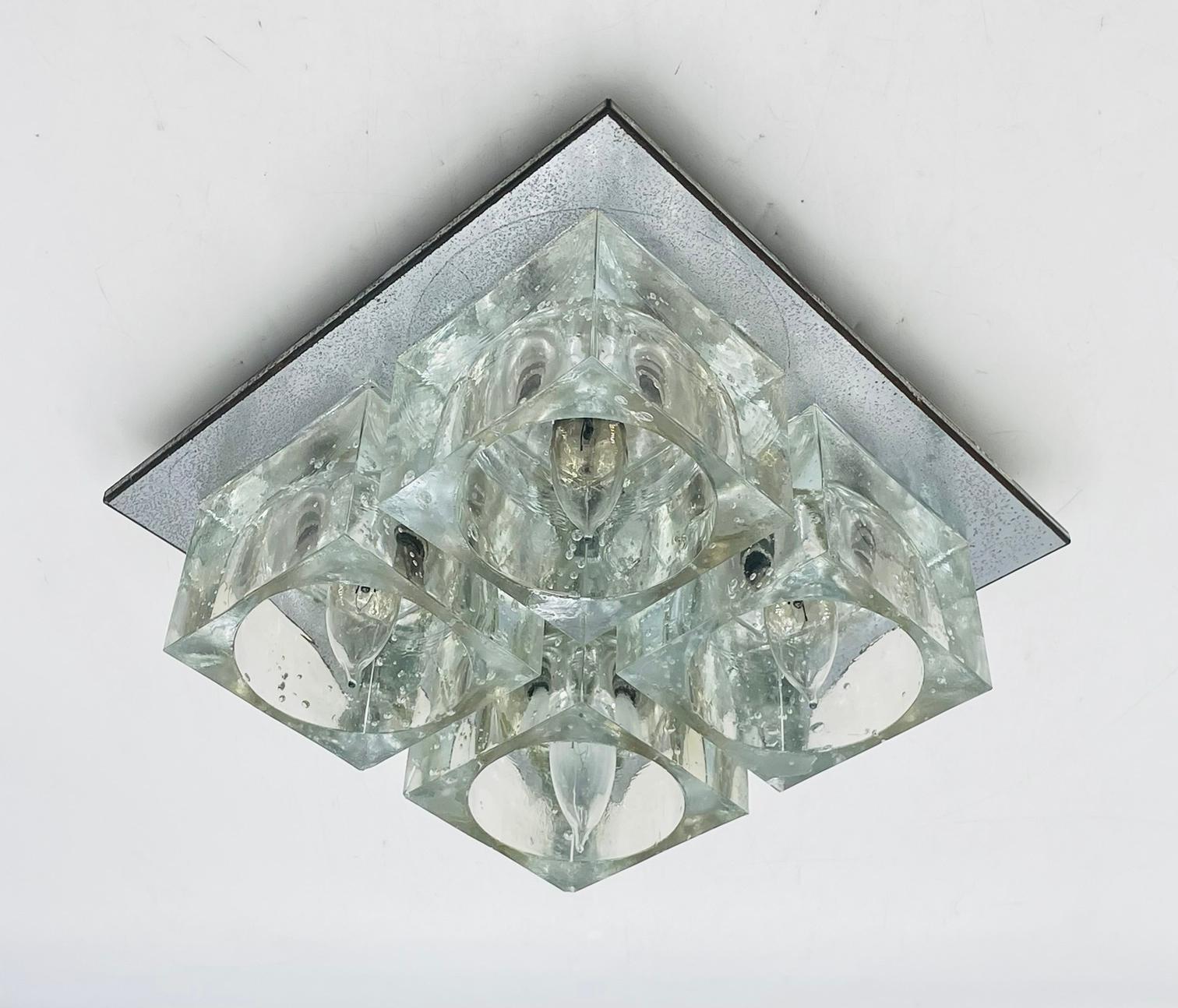 This brilliant Mid-Century Modern flush mount chandelier was realized by the esteemed Italian glass blower Gaetano Sciolari for Lightolier, circa 1970. It features four thick translucent Murano glass cubed shades with inset bulbs attached to a close