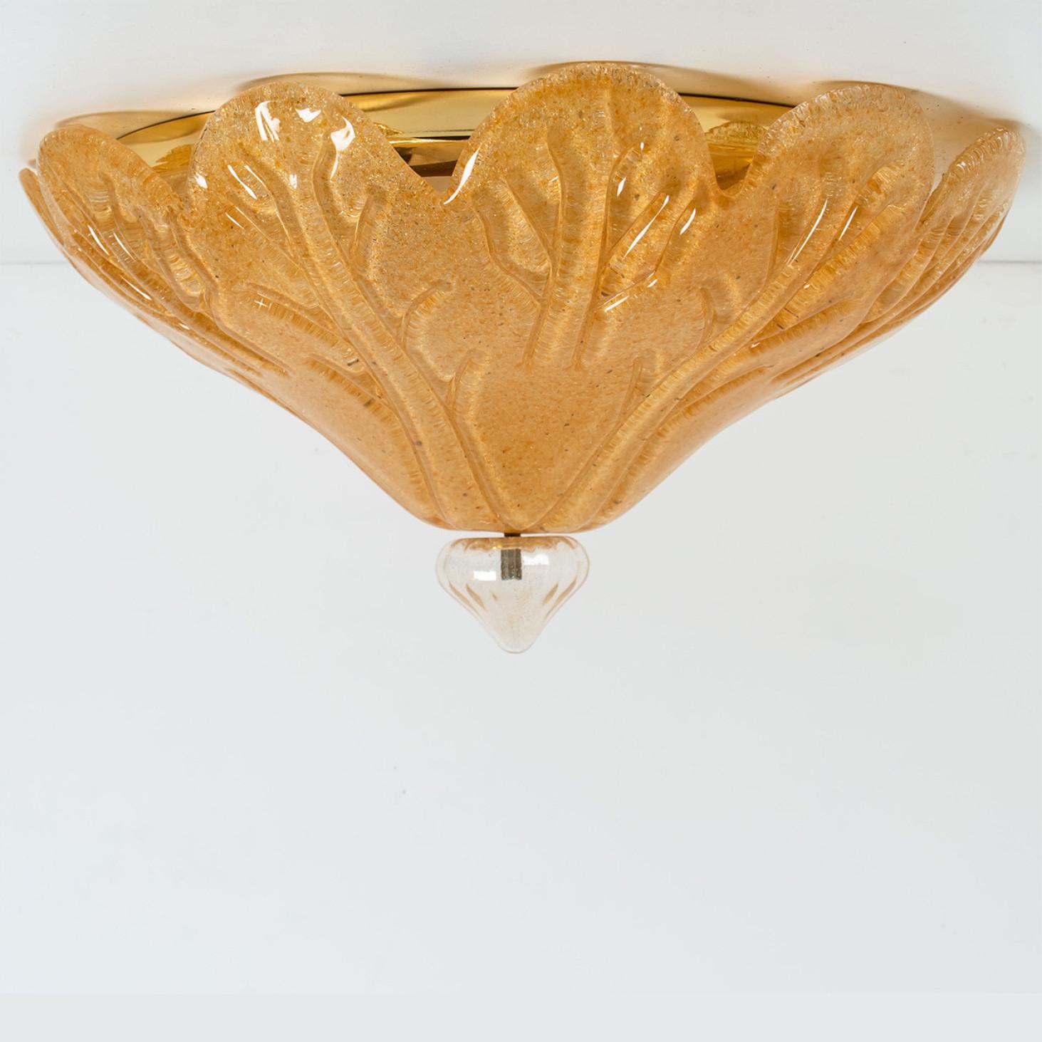 An elegant hand blown Murano glass flush mount , Italy, 1970s.
The leaf shaped glass is gold speckled and has a clear 'top' with gold speckles. Mounted on a golden brass frame. The textured glass refracts light beautifully.

The flush mount fills