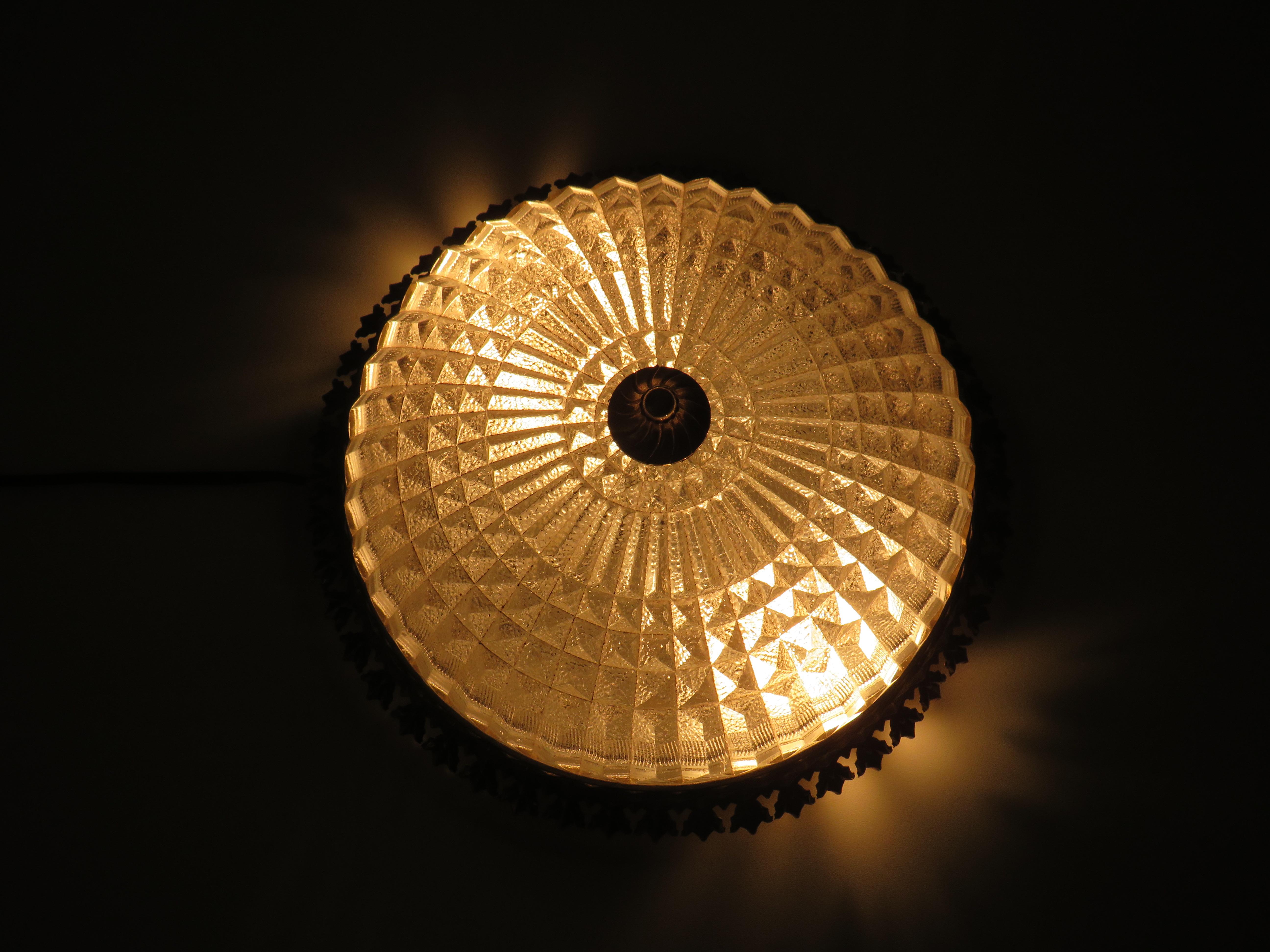 Round ceiling lamp in cut glass with geometric motif and gold-coloured brass edge with leaf motif.
The lamp is equipped with 2 E 14 porcelain fittings and the back plate has the necessary suspension holes.
The diameter of the item is 30 cm and the