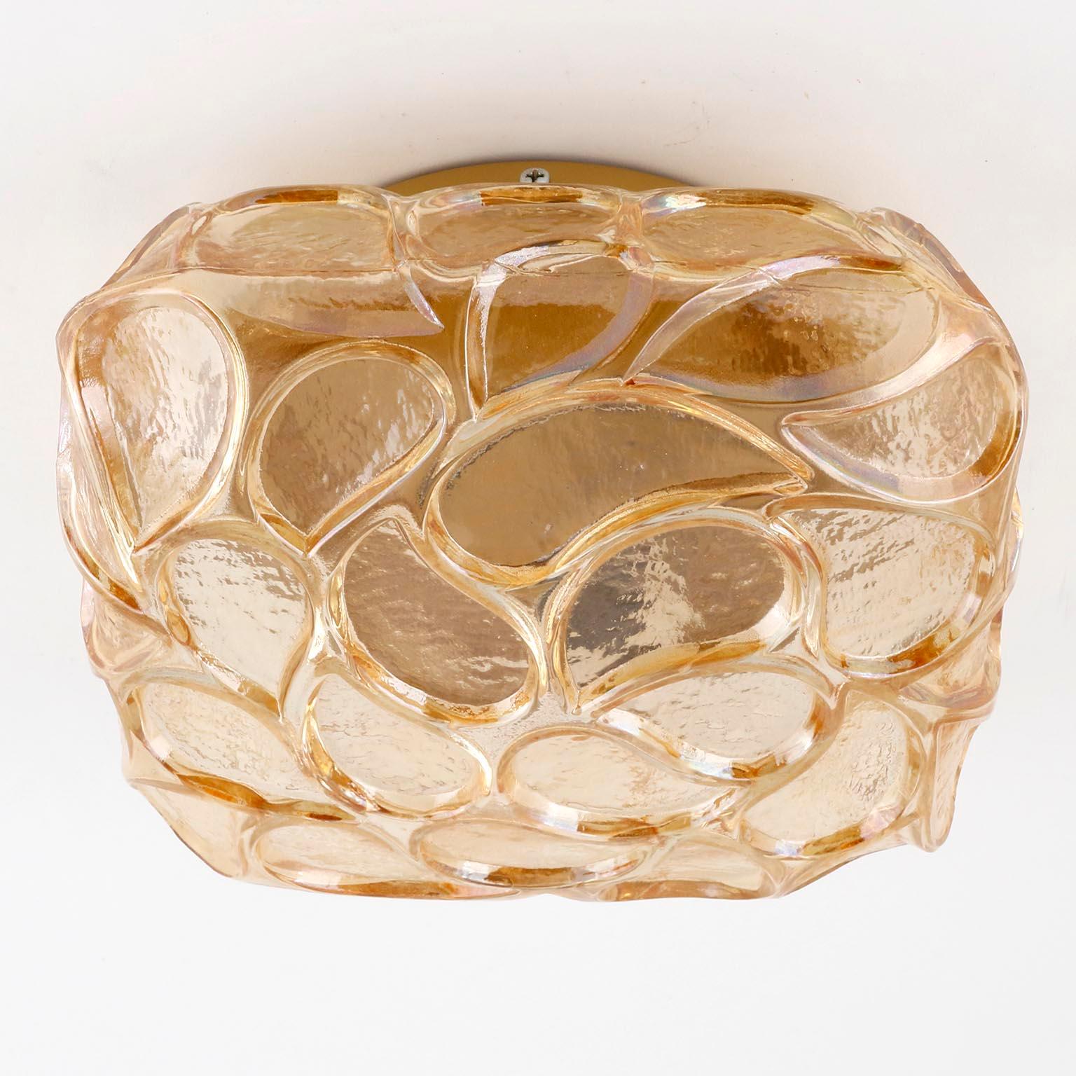 A fantastic square textured glass light fixture, manufactured in Germany in midcentury, circa 1970 (late 1960s or early 1970s).
An amber, yellow, orange, honey, champagne toned textured glass with Paisley pattern is mounted on a golden or brass