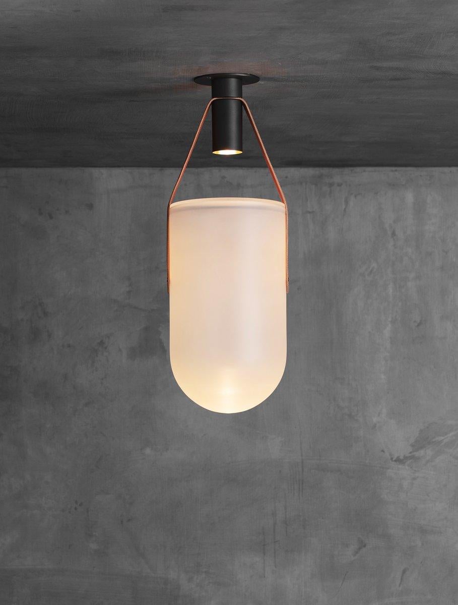 A spot bulb shoots light into a sandblasted glass dome that is suspended by a leather strap and brass hardware. The fixture creates a warm glow inside the glass as well as casting dramatic shadows onto the ceiling. UL certified.

Handcrafted in