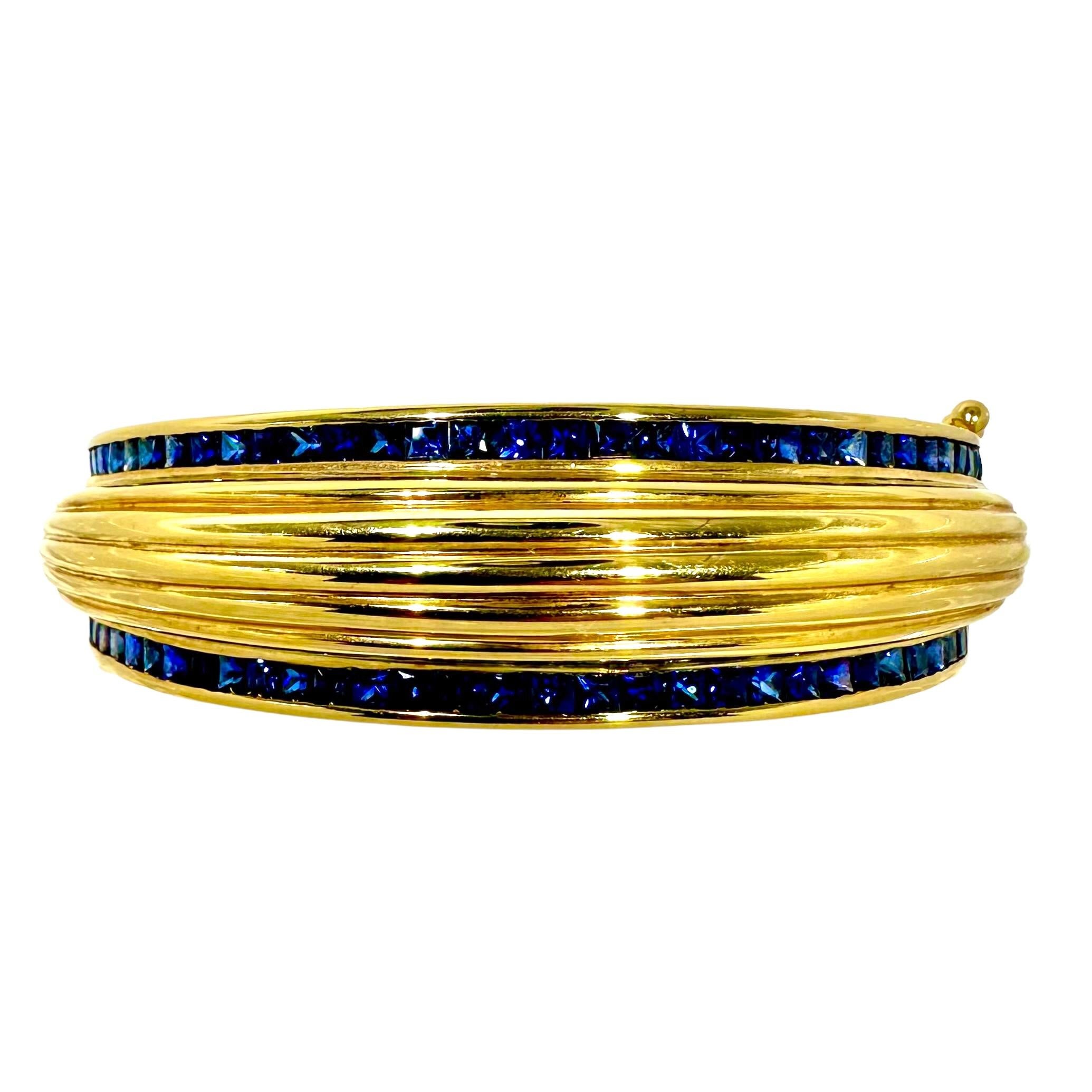 Un fabuleux bracelet en or cannelé et bombe, réalisé en or jaune 18 carats. La partie centrale nervurée est ensuite associée à des lignes droites de saphirs bleus profonds sertis en canal qui bordent le haut et le bas. Mesure de 11/16 de 
Avec un