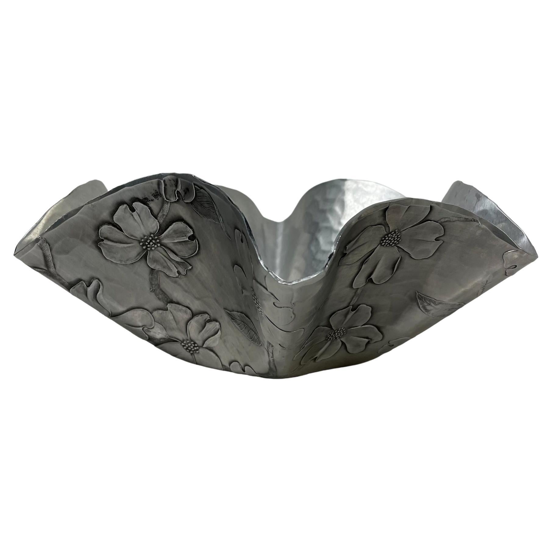 Sculptural dish
Handmade by Wendell August craftsmen in hammered aluminum collectible dish candy or catch it all.
from Grove City, Pennsylvania 
Wonderful flair with pretty dogwood floral motif.
Measures: 3.88 height x 10.5 diameter
Original