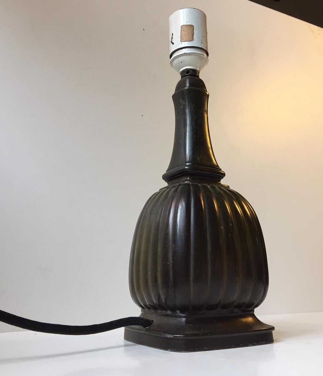 This baluster-shaped table lamp with a partially fluted corpus dates to the 1930s and was made in Denmark. The lamp is made from diskometal, which is an alloy invented by Just Andersen and mimics the green/dark patination of bronze. The base is
