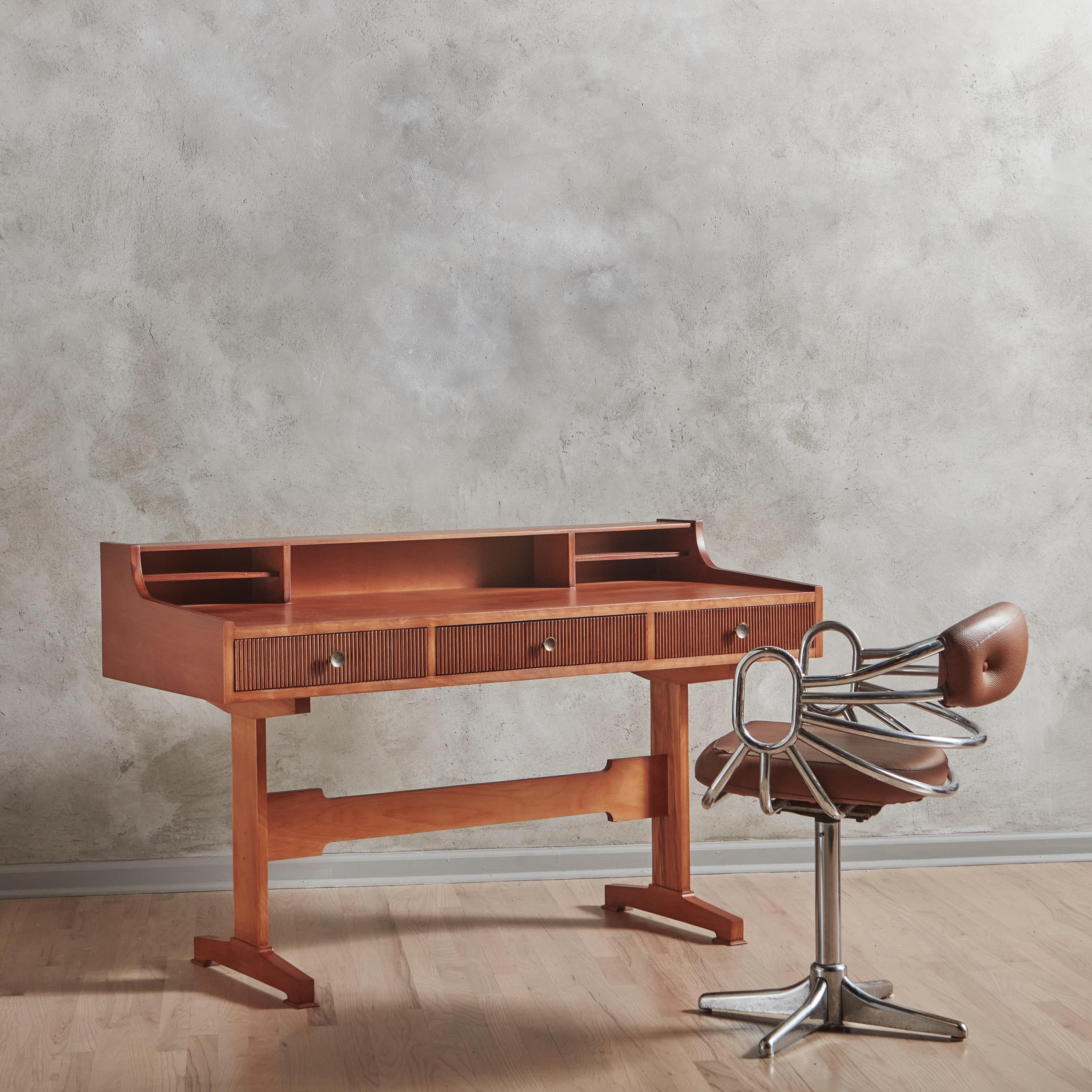 Fluted Beechwood Writing Desk in the Style of Gianfranco Frattini, Italy 1950s

The double footed legs is reminiscent of Frattini’s lines. The “grissinato” technique (in front of the drawers) is a mesmerizing and typical 1950’s Italian detail that