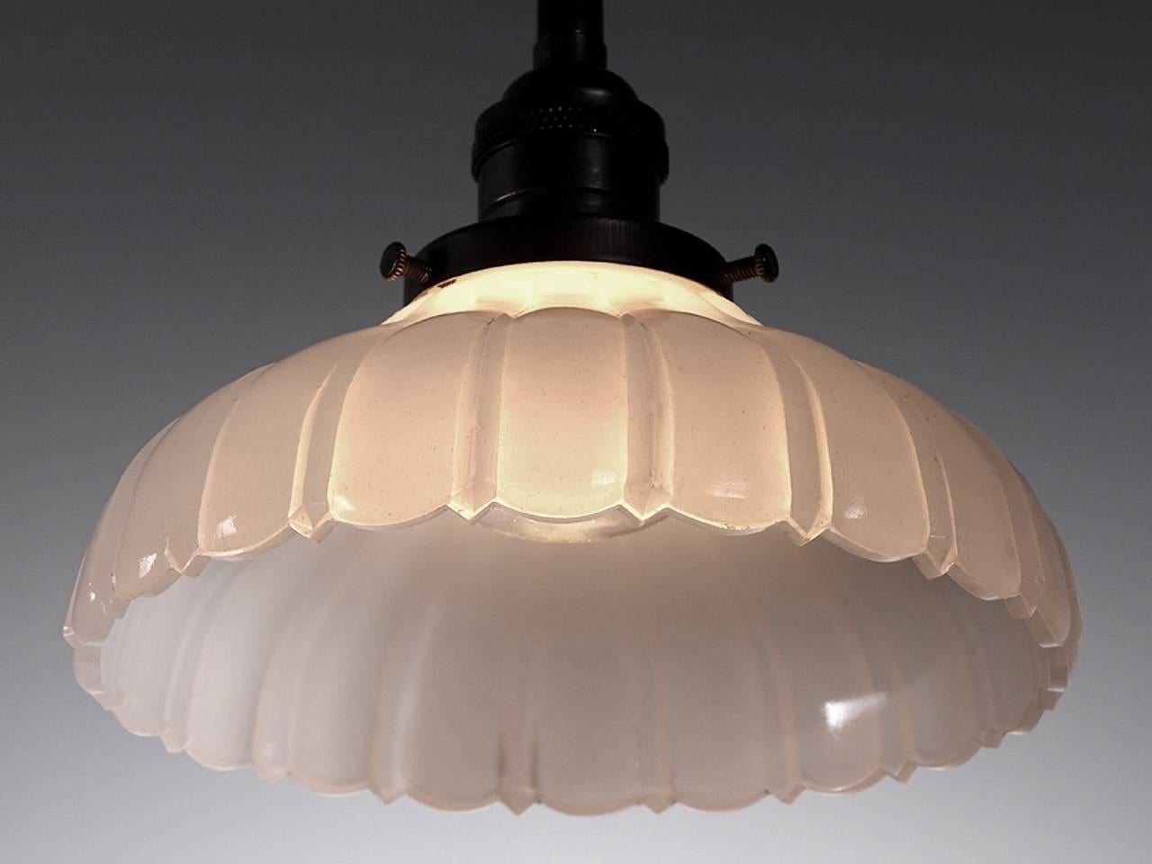 Softly curved bell shaped pendants are a Classic. They feel at home with any style decor. This example is an extra heavy thick-thin pattern in cast Clam Broth glass with a scalloped edge. The lamps are priced as a pair.