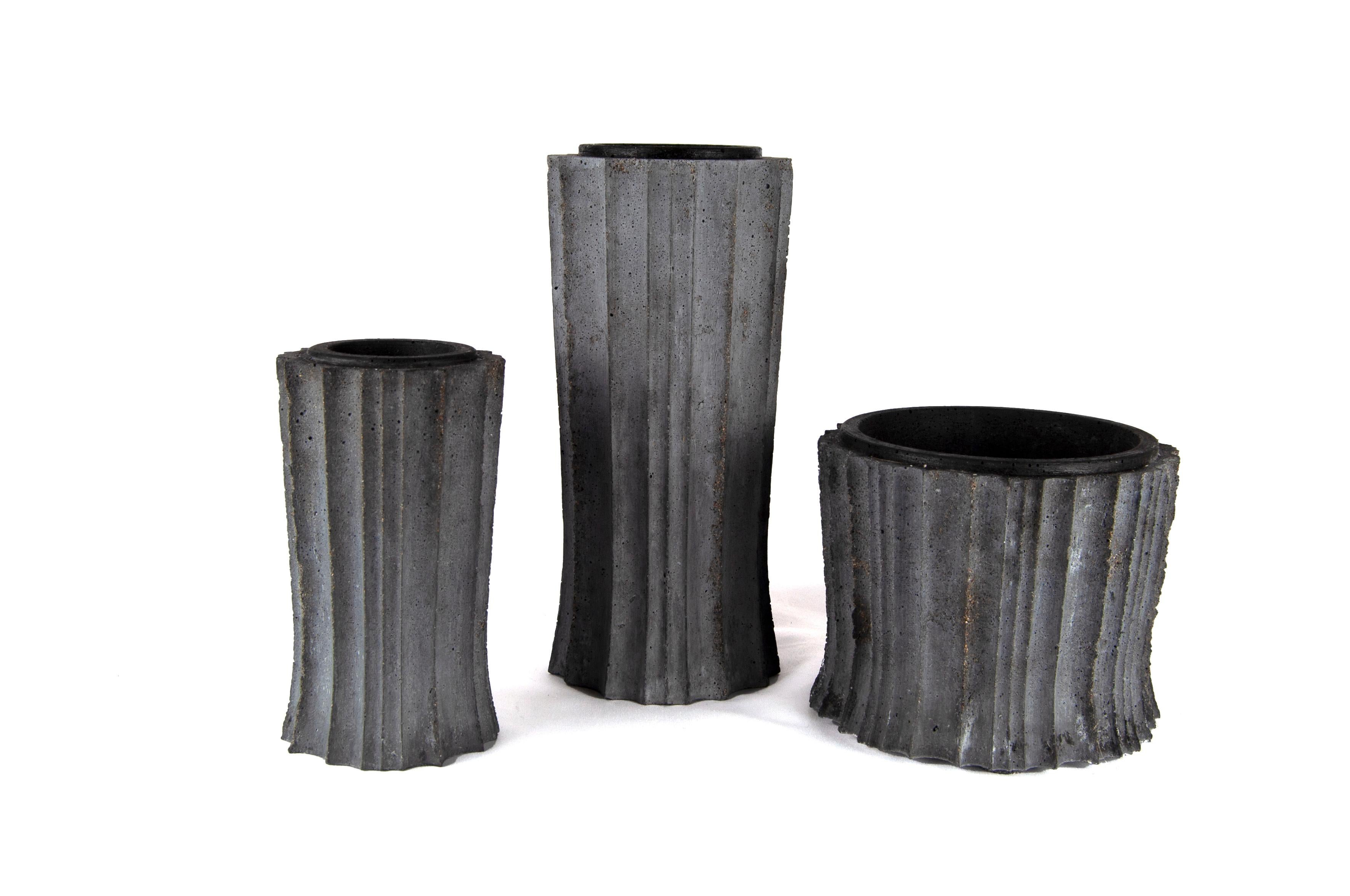 Ein bisschen Art Deco, ein bisschen Gotik, sehr brutal. Gegossener Beton, mit dunkelgrauem Pigment eingefärbt. Natürliche Oberfläche. 

Diese Gefäße sind leer sehr schön, aber noch besser mit Blumen oder einer Sukkulentenbepflanzung. 

Kleine