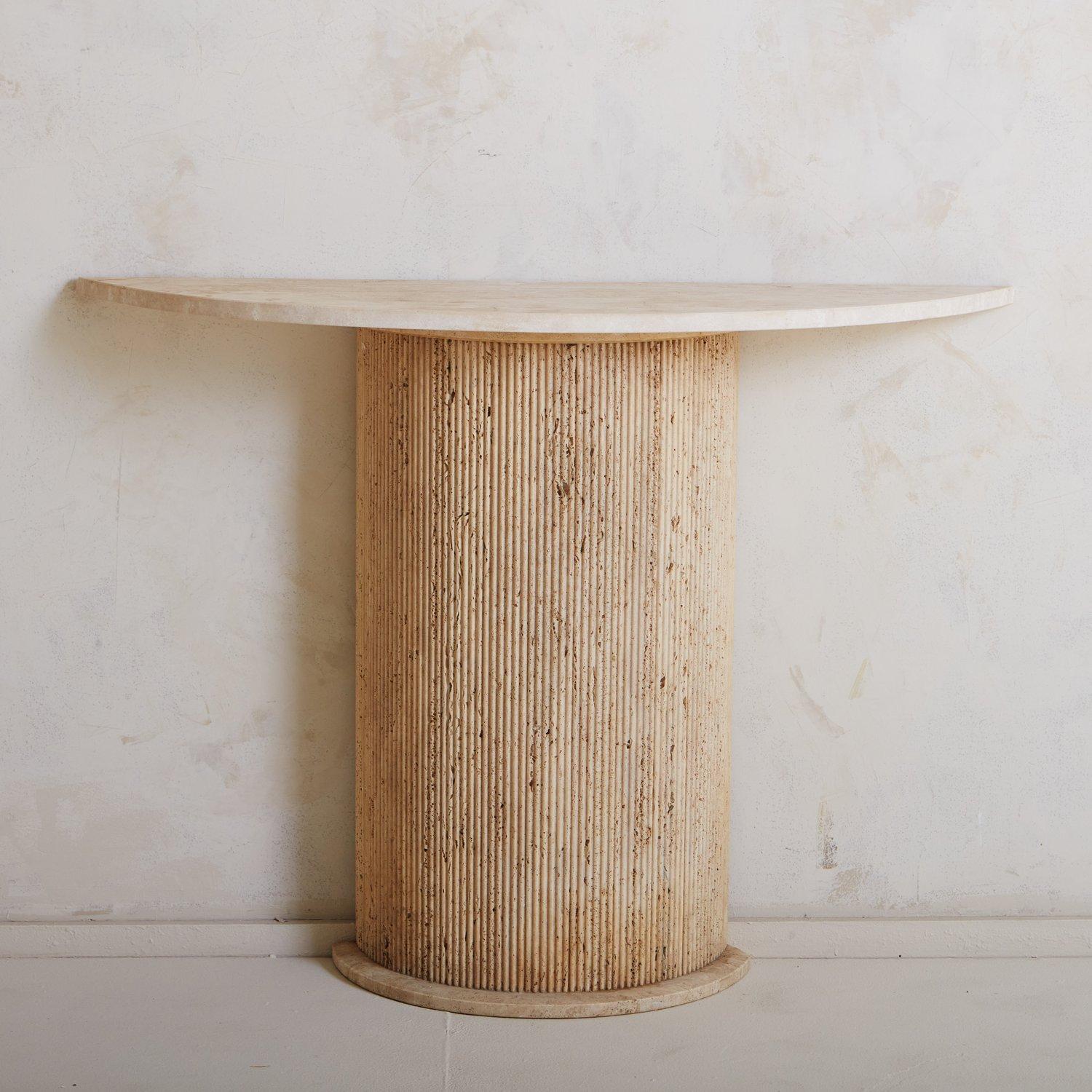 A vintage travertine console featuring a demilune shape with a fluted base and band detail. We love the variation in the unfilled travertine base and range of taupe hues. Sourced in Spain, 20th Century.
