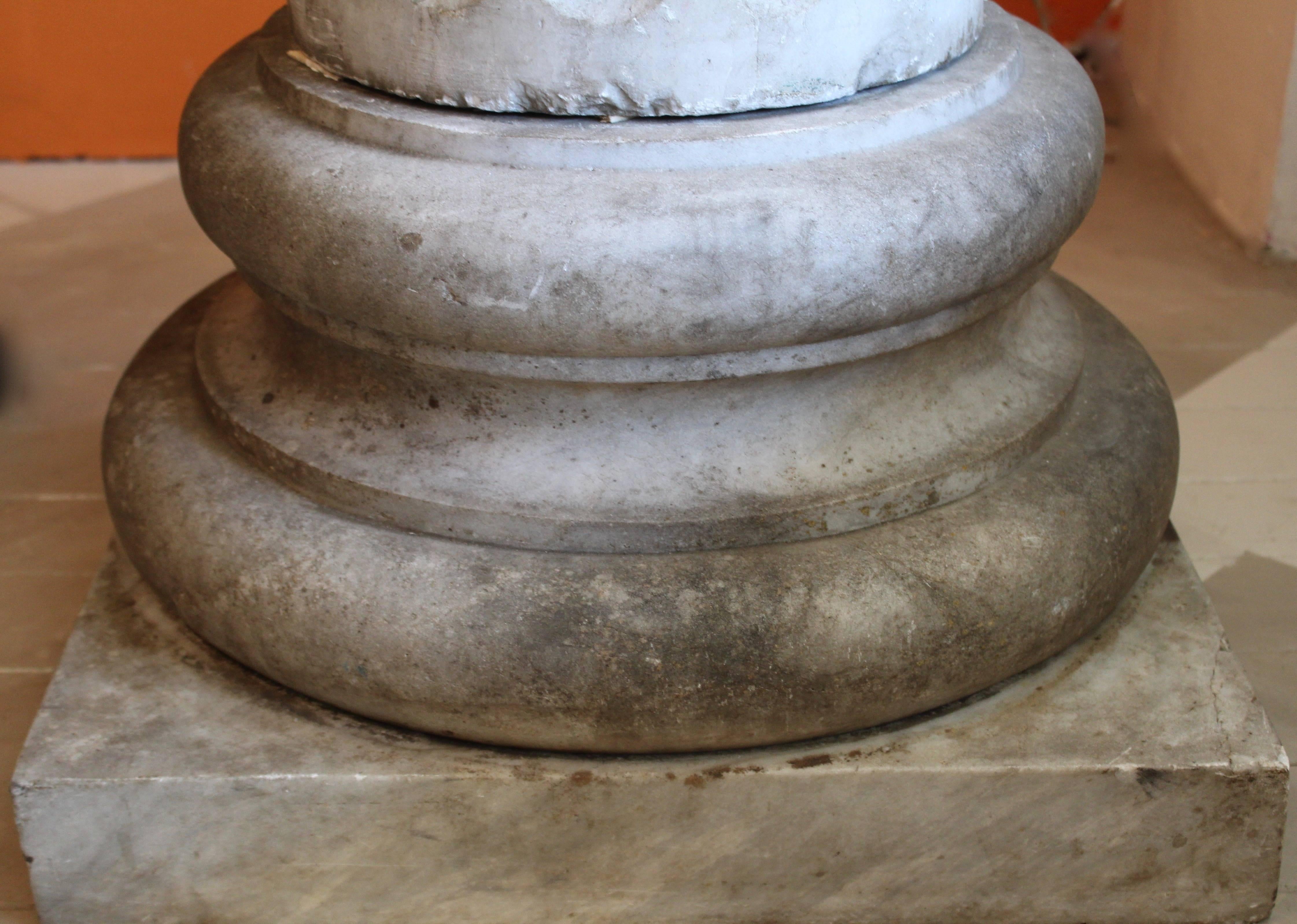 An oversize Carrara marble column from France, circa 1890. Topped with a square section of marble above a classic Ionic capital. This is characterized by the volutes; the symmetrical scrolls on either side of the capital, which then leads down to