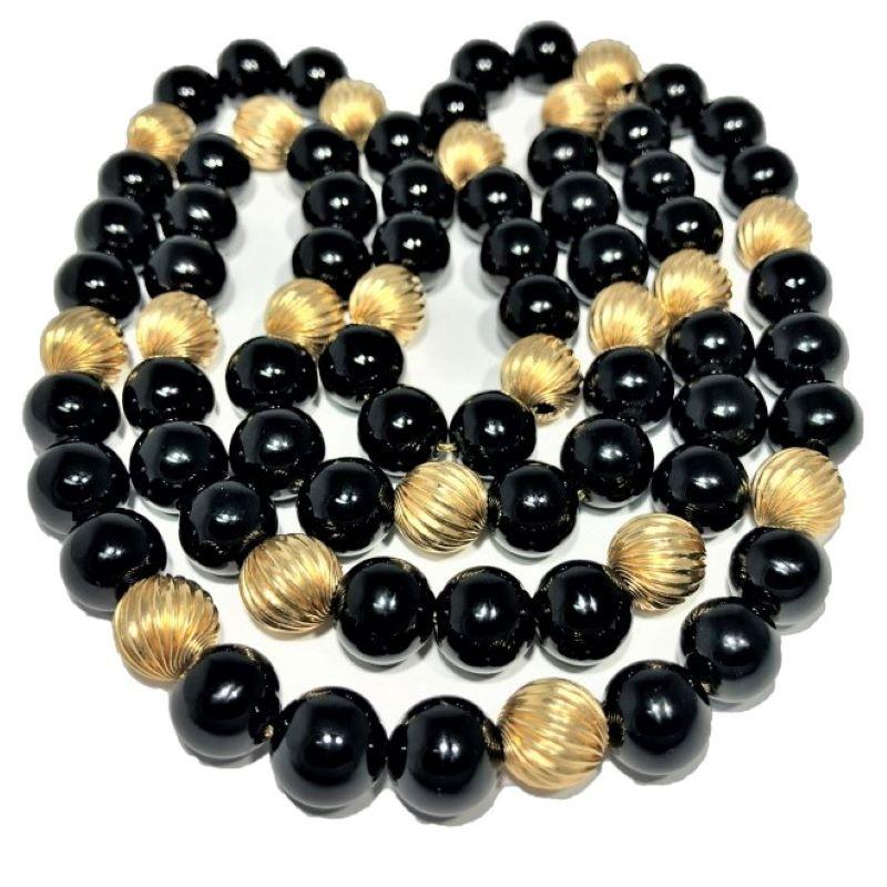 This striking necklace is a continuous 32 inch length of beautifully symmetrical, high polish, round, 10.5mm black onyx beads interrupted by one 10mm 14k yellow gold 
