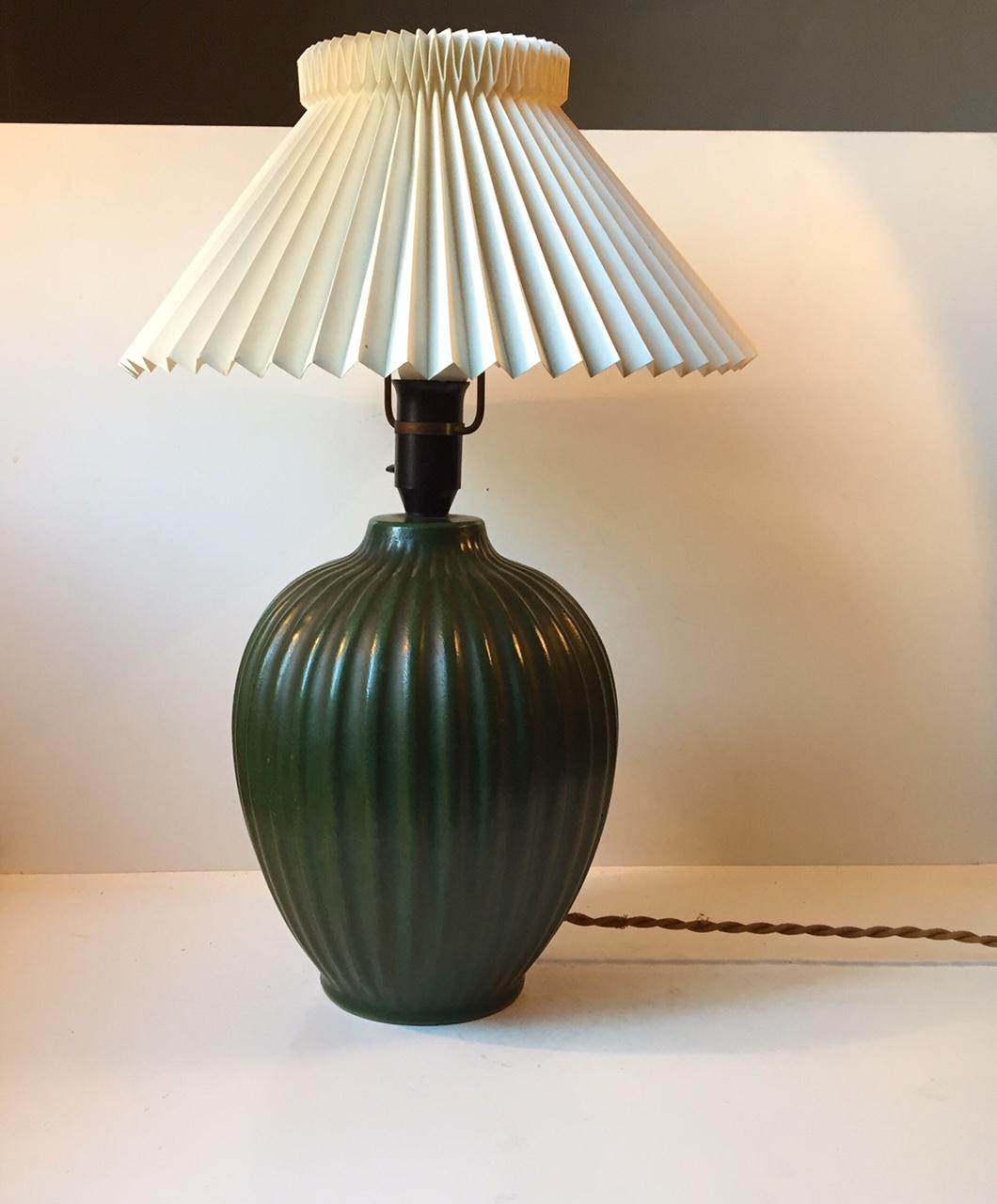 From a distance this lamp looks like its made of bronze. However its all ceramic that has been applied with a verdigris green glaze to its vertically fluted body. This rare table lamp base was made by Michael Andersen in Denmark during the late