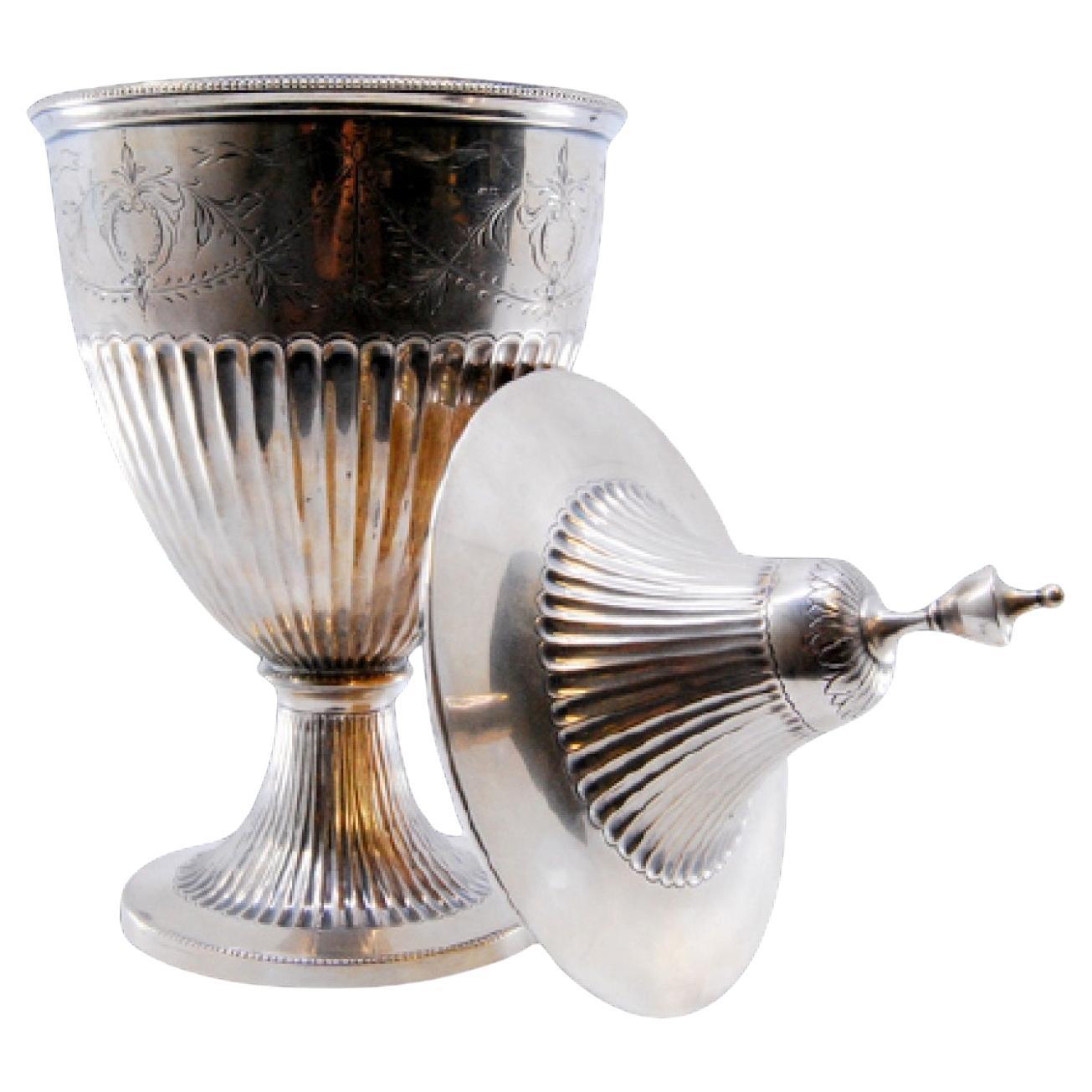 Descrizione: Bonboneiro d'argento scanalato a basso rilievo con incisioni e appoggiato su una base rotonda. Metallo: Argento. Origine: Portoghese. Marchio: Porto Eagle Testa. Peso: 386,83 grammi. Dimensioni: 23x8,4 cm. Contenuto: 833/1000. Marchio