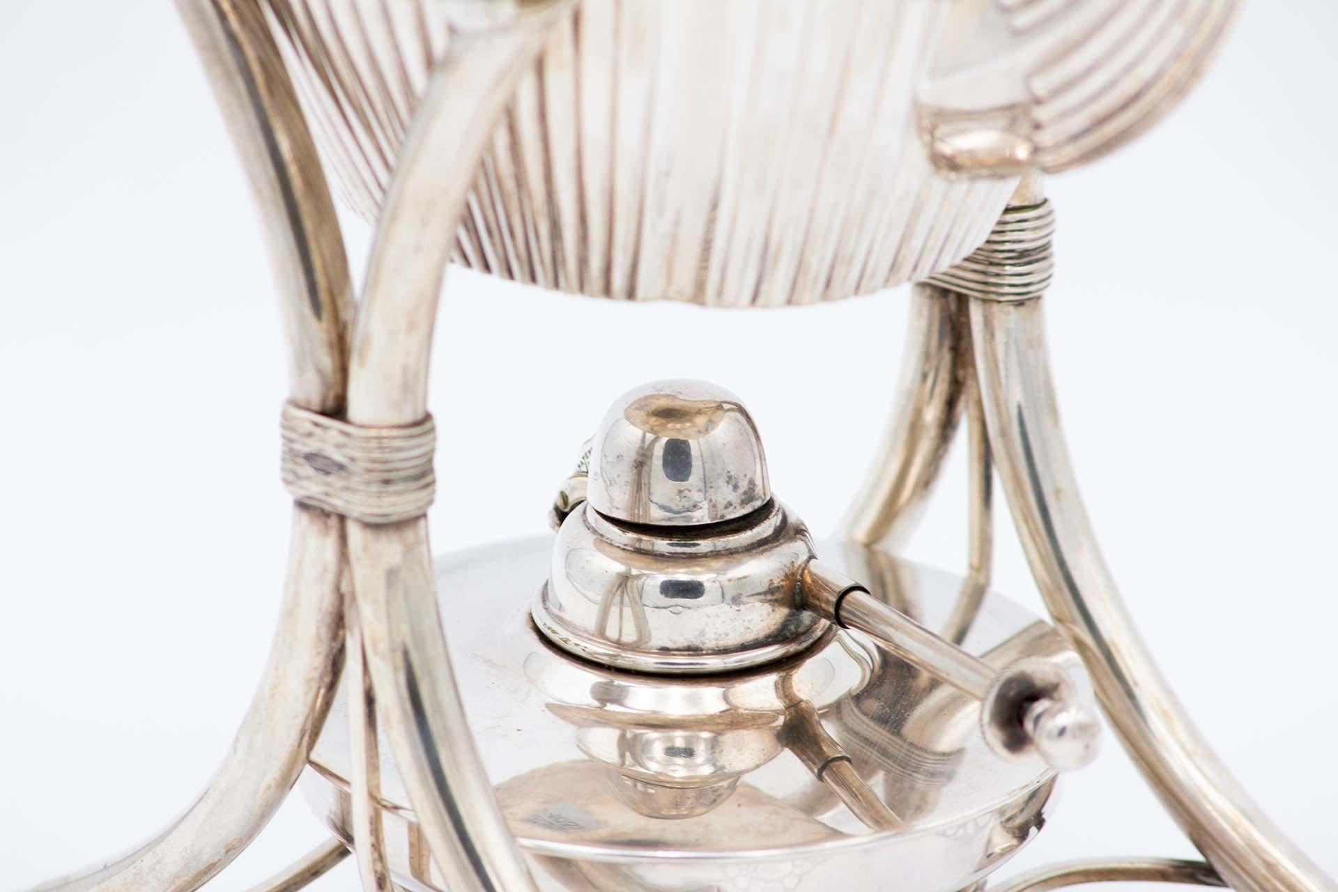 Description : Bouilloire en argent cannelé suspendue à un dessous de plat, avec quatre pieds circulaires surélevés, lampe et poignée avec application en bois de châtaignier. Métal : Argent. Origine : Portugais. Marque : javali II Titre. Poids :