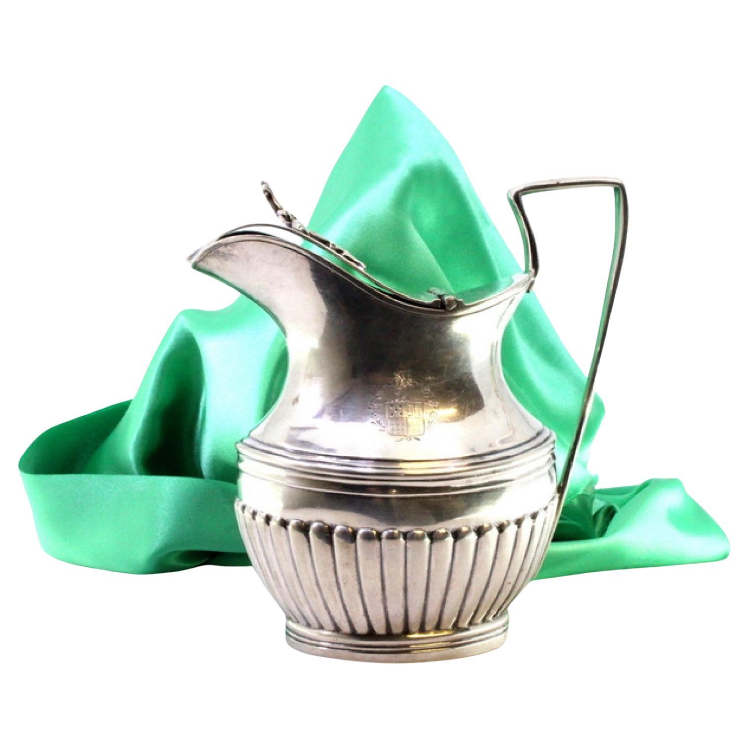 Fluted silver milk jug with coat of arms, knobbed lid, and trim For Sale