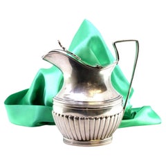 Fluted silver milk jug with coat of arms, knobbed lid, and trim