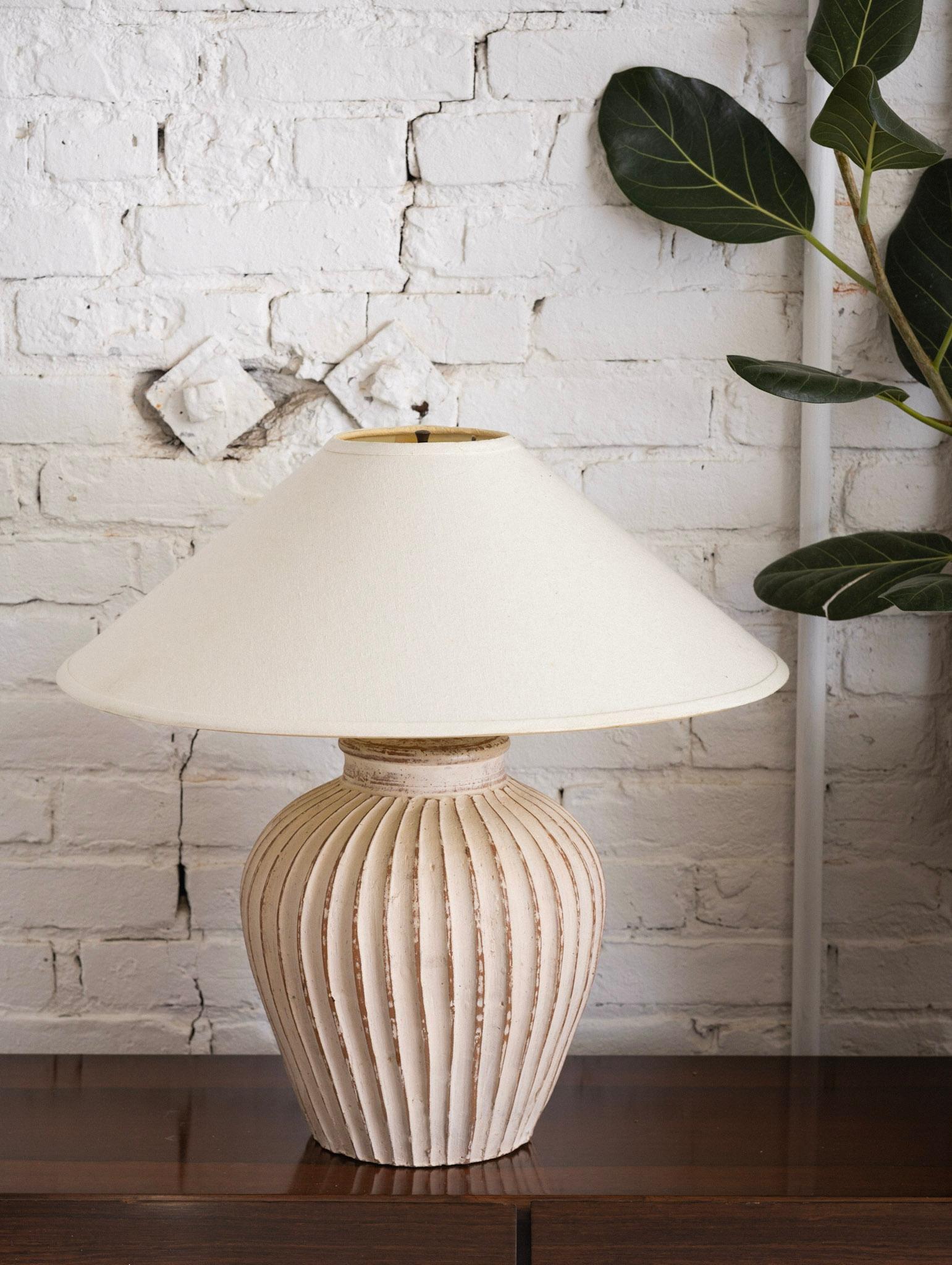 A terra-cotta table lamp with fluted detail and white wash finish. Harp and finial included. Shade NOT included. Measured from base to top of finial.