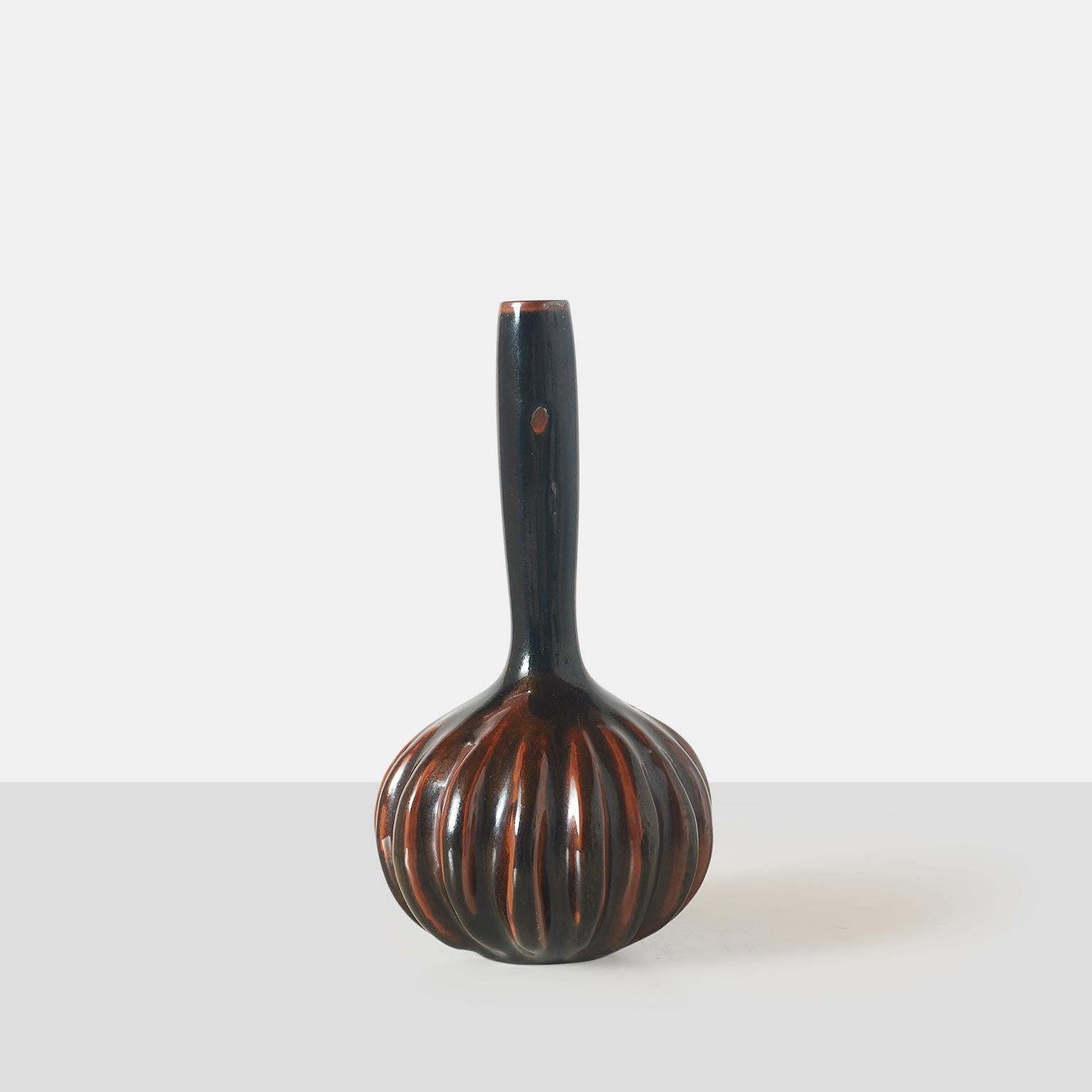 A stoneware vase by Axel Salto for Royal Copenhagen with a long slim neck and fluted base and decorated with a deep red and brown olivine glaze. Signed SALTO on the base.