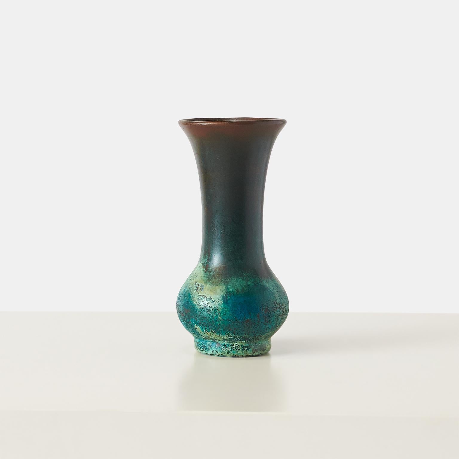 A fluted copper cladded clay vase with bronze and verdigris patina. 

By 1909, Clewell had perfected his own distinctive method of covering a clay vessel with a tight shroud, usually of bronze or copper. He never shared the secret of how to