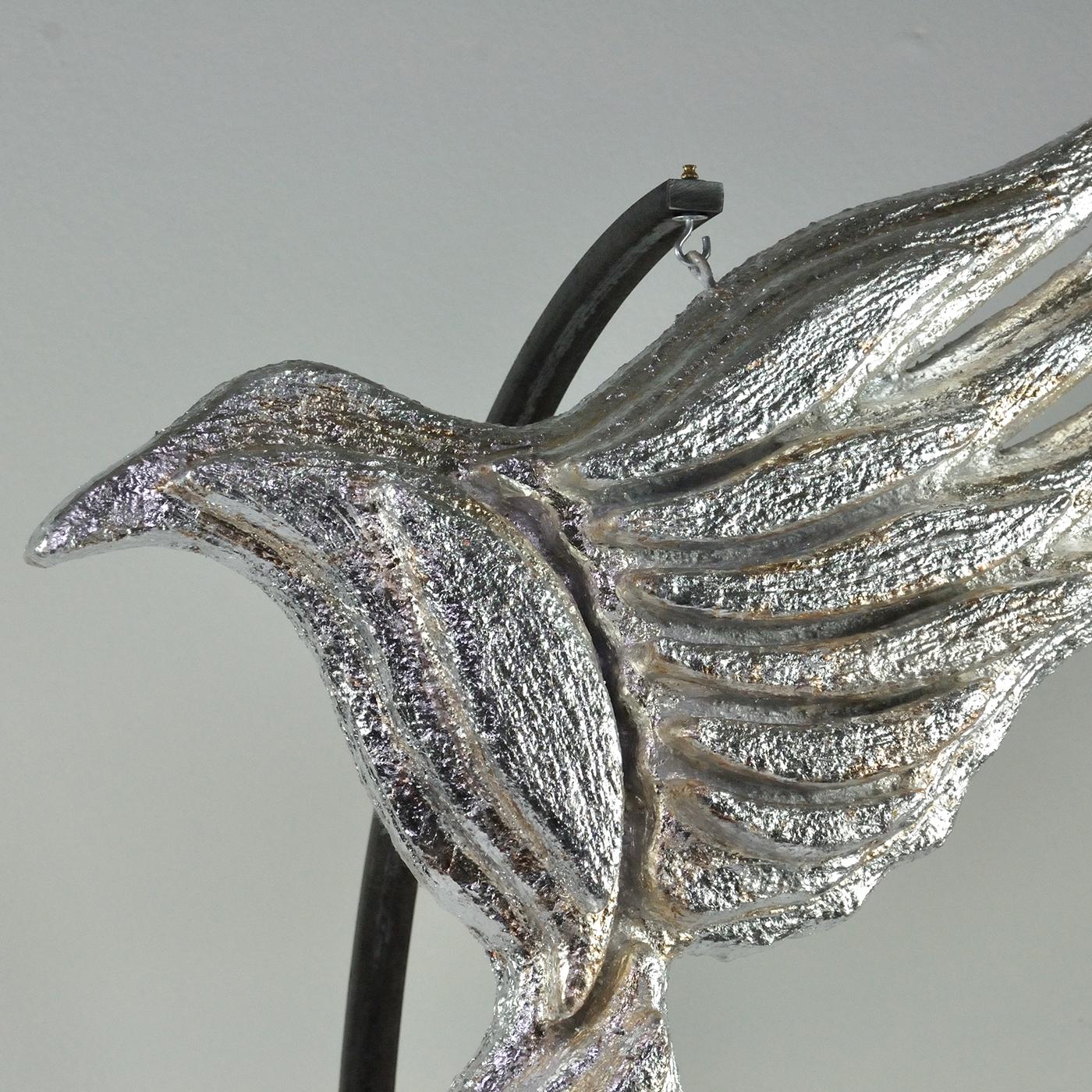 An ode to freedom, this sculpture flaunts a sinuous bird captured right before flapping its wings. Precious silver leaf covers its entire body, lending a stunning shimmering quality and enhancing the texture obtained with the application of plaster
