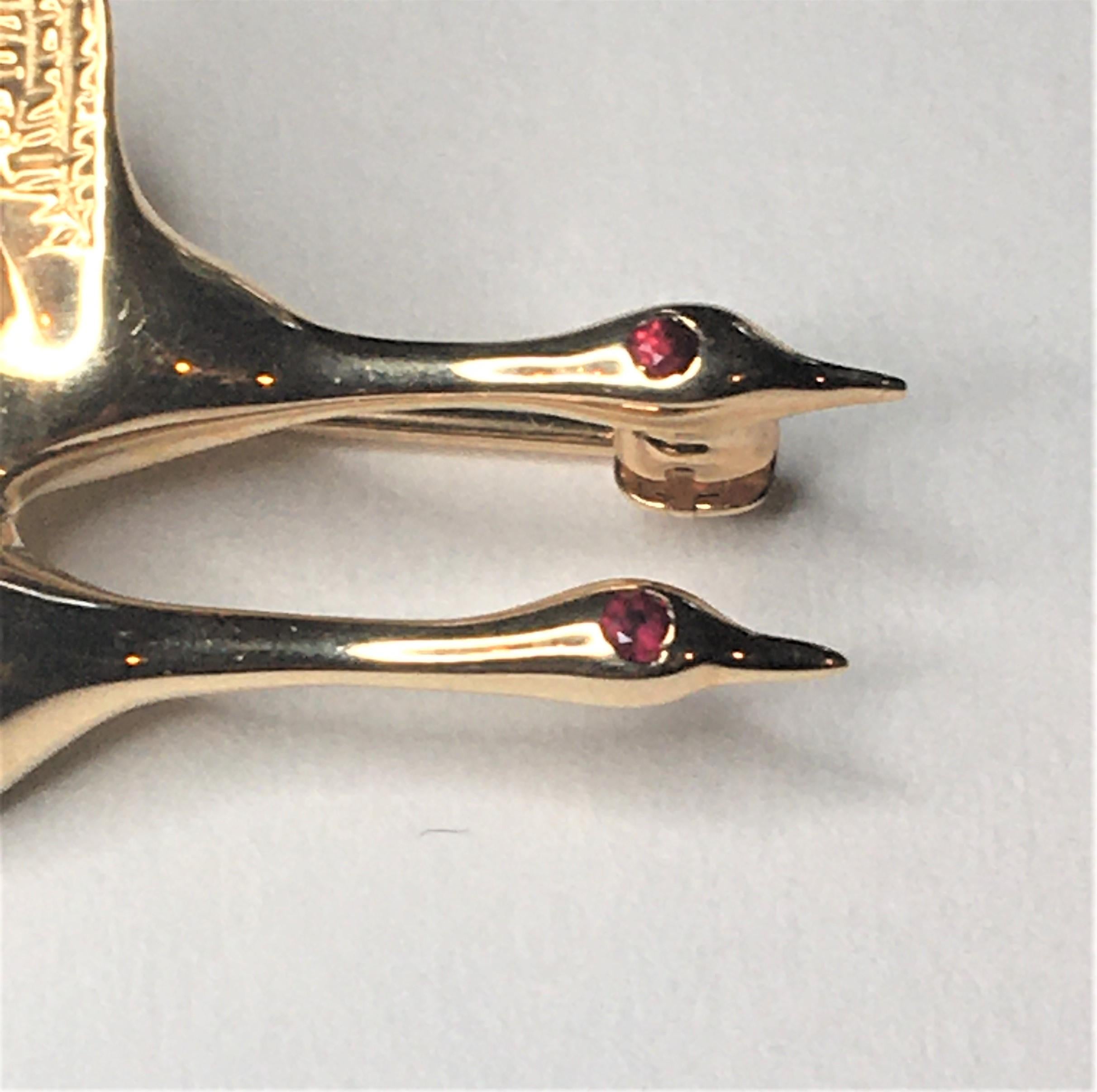 This small brooch would be a great addition to any coat, scarf or shirt!
Designer Robert Fisher & Co.
Two flying geese with wings high and necks reaching out.
14 karat yellow gold
Two round rubies for the 