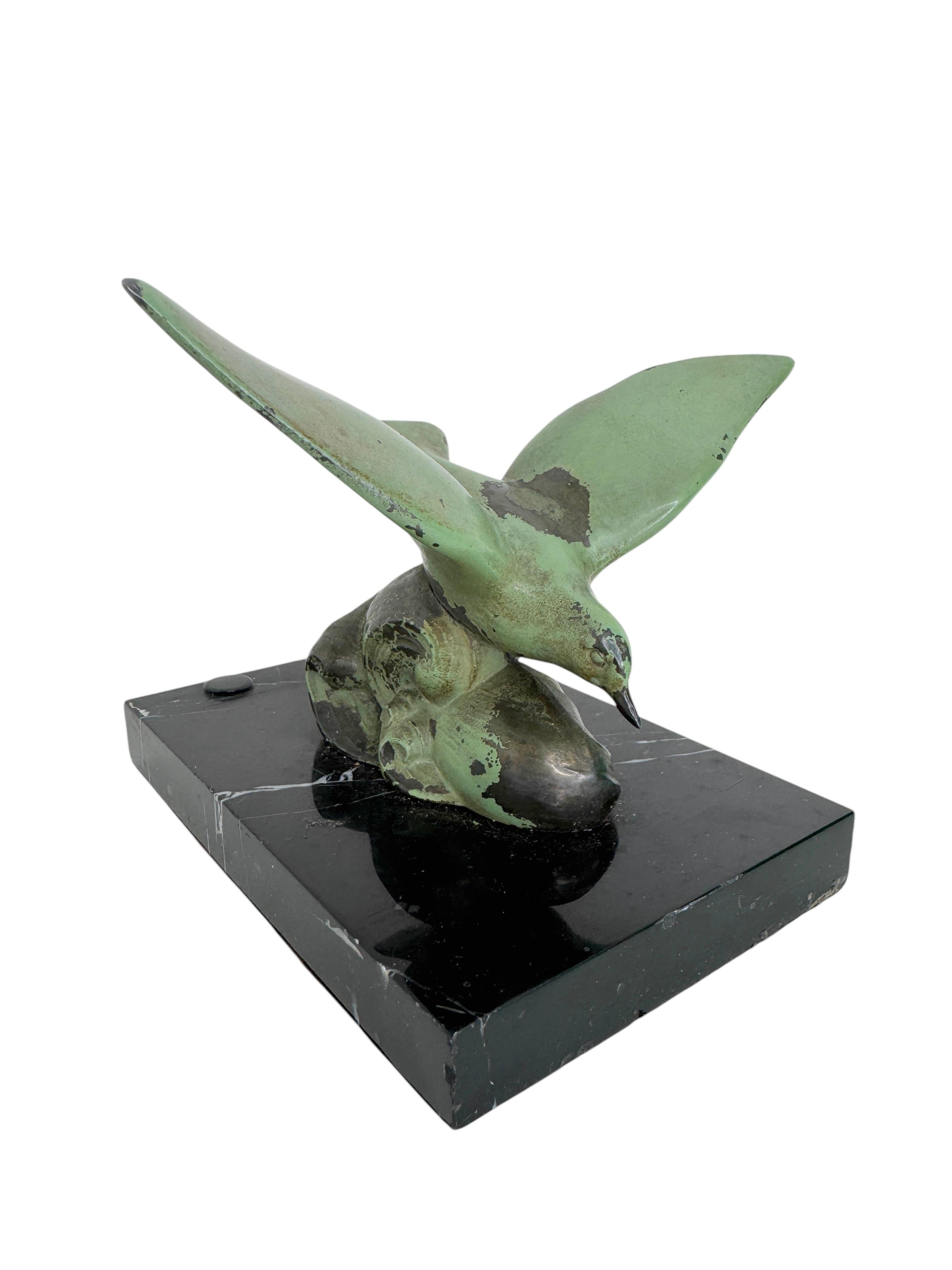 Sculpture en bronze patiné vert-de-gris du début du 20e siècle représentant une mouette volante frôlant la crête d'une vague, montée sur une base en marbre noir. original de la période Art déco. Vous pouvez également l'utiliser comme presse-papier