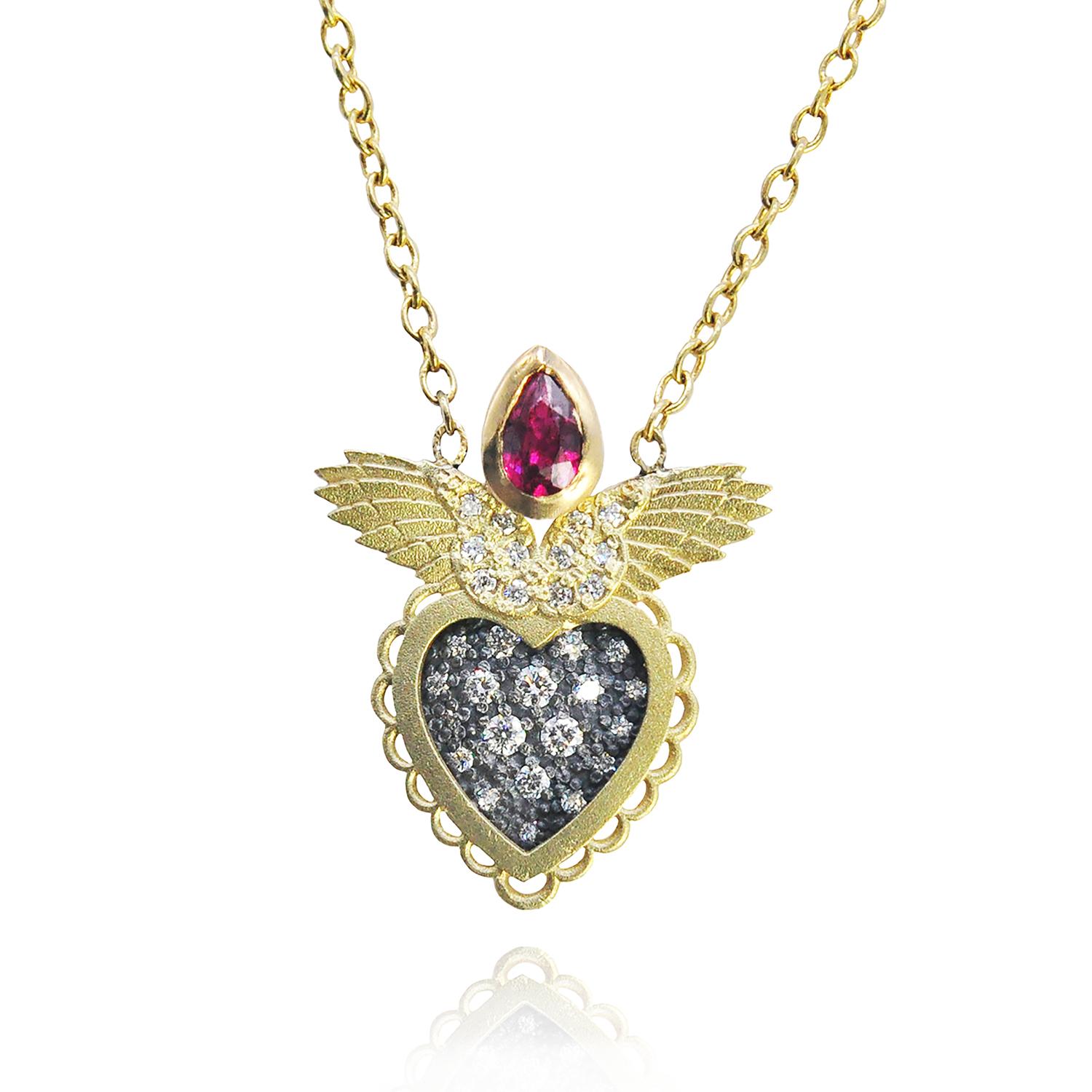 Oxidized silver center glimmers with pave set white diamonds inside a bright 18k yellow gold scalloped valentine style heart. Our signature 18k yellow gold wings are topped with a juicy red, faceted, pear shaped ruby and more pave set white