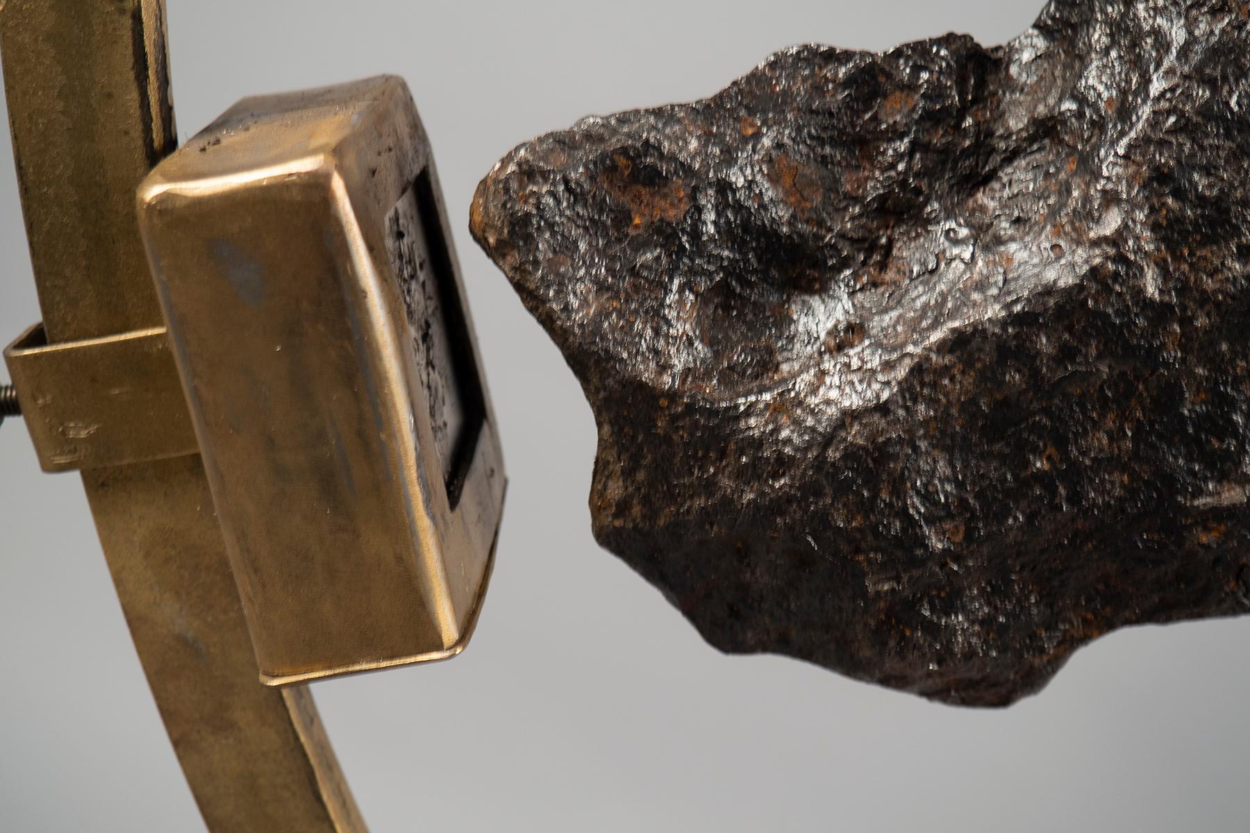Grande structure en laiton de 3/4 de cercle contenant un fragment de météorite (5 kg) provenant de Campo del Cielo, Argentine. La météorite est maintenue en place par un puissant aimant en terres rares monté sur la structure. La base est une boîte