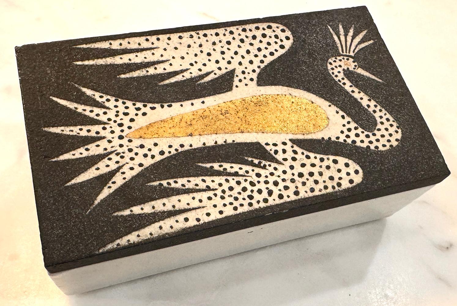 Questa scatola con coperchio in porcellana pesante di Waylande Gregory raffigura un uccello Phoenix crestato in volo, con le piume punteggiate di nero e le ali rivestite d'oro.  Gregory è stato uno dei più grandi scultori e ceramisti americani prima