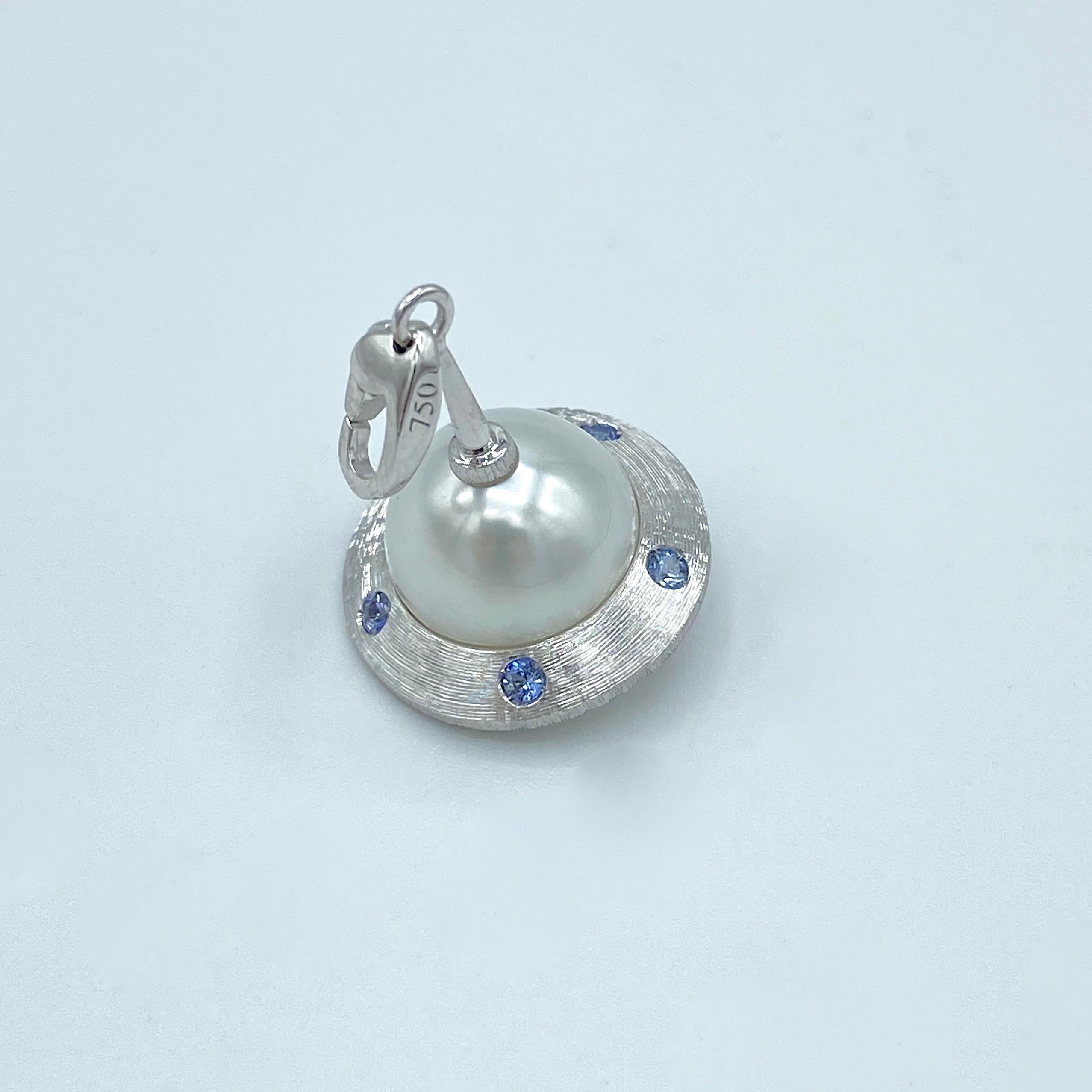 Flying Saucer Blue Sapphire Australian Pearl 18KT Gold Pendant Necklace or Charm

I use a n Australian lightly button pearl (mm 11x12,5) to make a flying saucer.
The white gold structure is engraved by hand and has 5 blue sapphires and in total they
