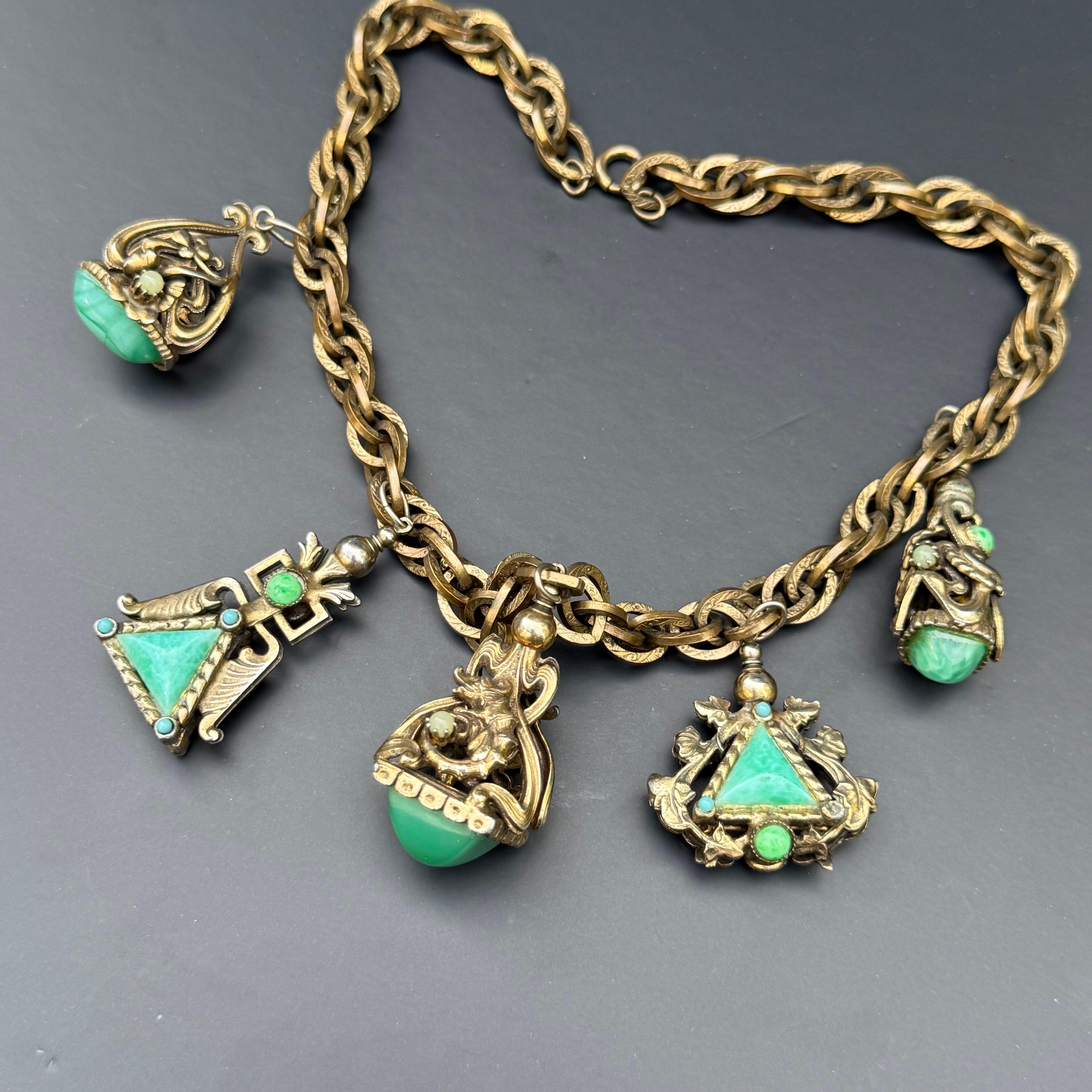 Step back in time with this beautifully evocative vintage charm necklace, dating to the 1960s and styled in the spirit of Victorian and Renaissance revival. This ornate piece features five unique fob-style charms, each adorned with detailed glass
