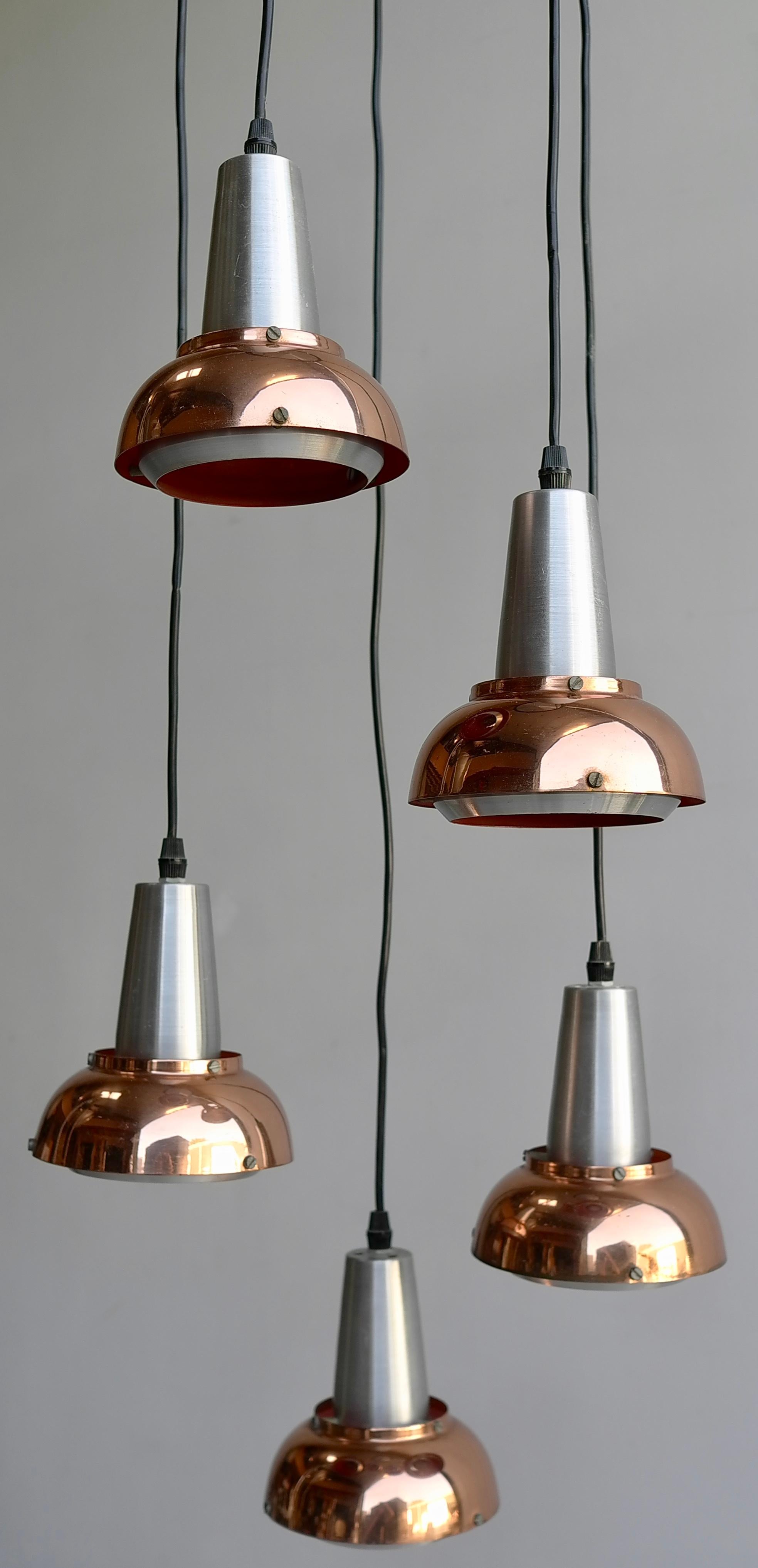 Copper and aluminium Fog & Morup 1960s chandelier. Each shade can be hung at a different height and level. Red colored inside each shade, it gives a warm light when lit.

Measures: Adjustable in height 110cm up to 150cm in total. Each shade is
