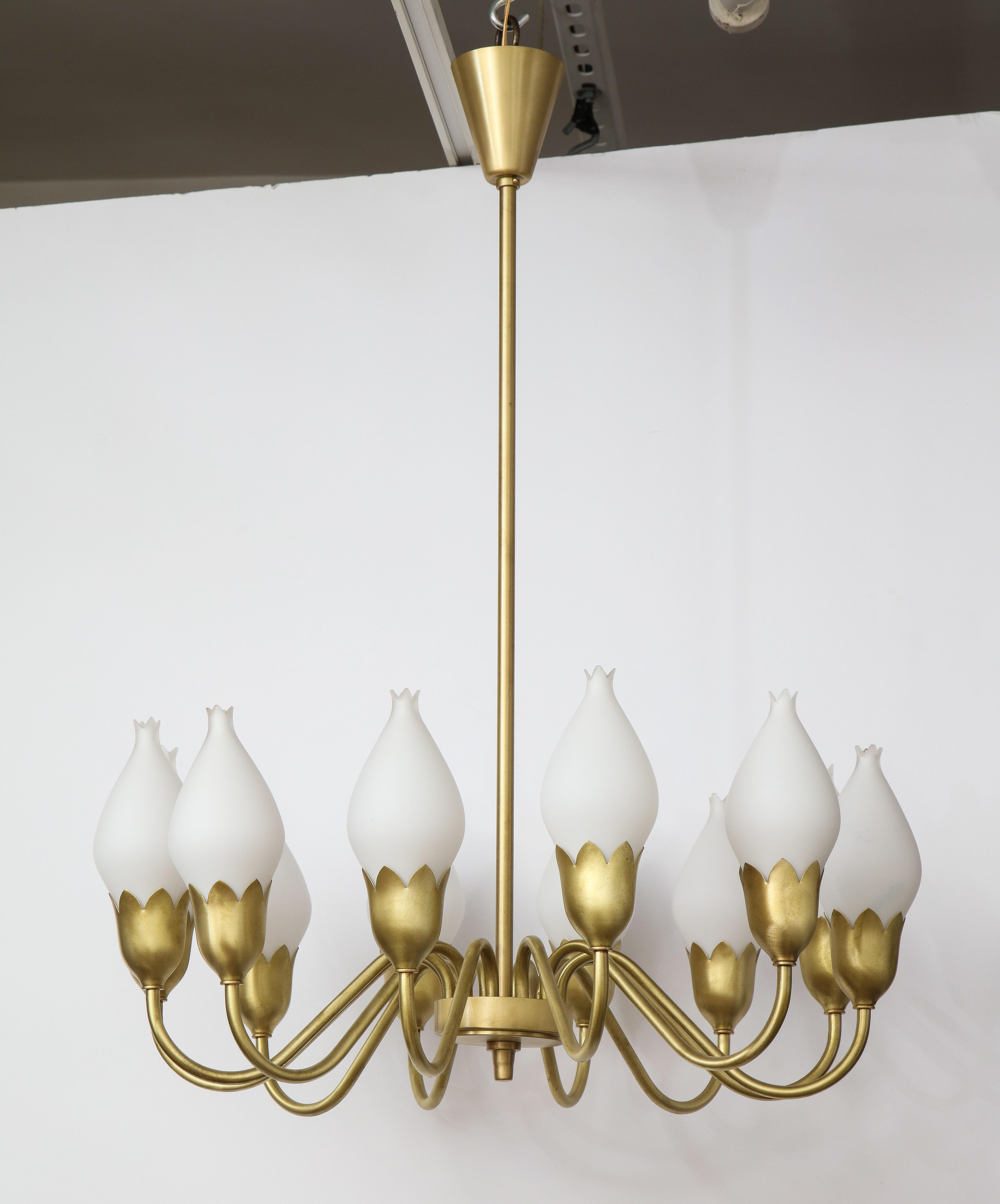 Danish modern chandelier featuring a satin brass armiture supporting 12 stylized white opaline glass 