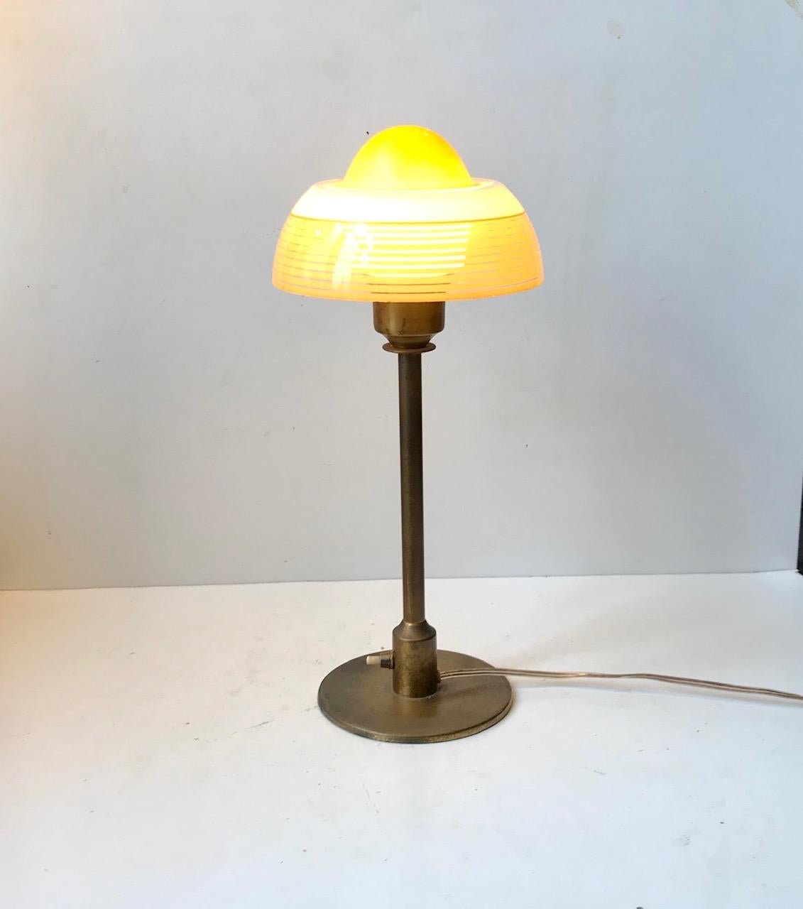 Danish Art Deco table light manufactured by Fog and Mørup during the 1930s. Its made from patinated brass and features a single layered, partially painted glass shade that resembles a fried egg - hence its name. This design is similar to lamps from