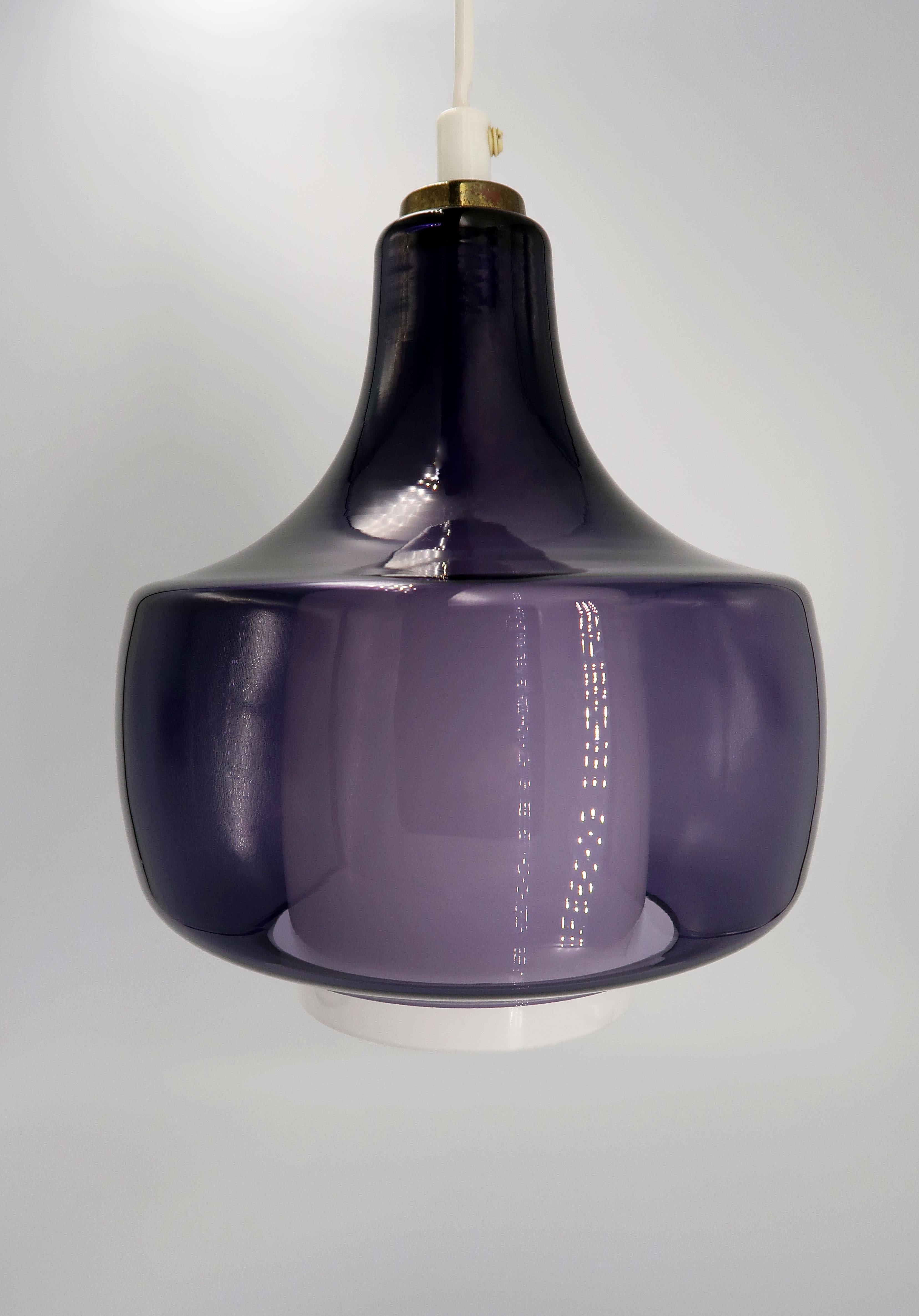 Beautiful Danish Mid-Century Modern purple glass pendant by designer Bent Nordsted for acclaimed Danish lighting manufacturer Fog & Mørup. Manufactured in 1968. Purple glass over white opaline glass with brass top. Model Kora E 2404/6022. Max 60W.