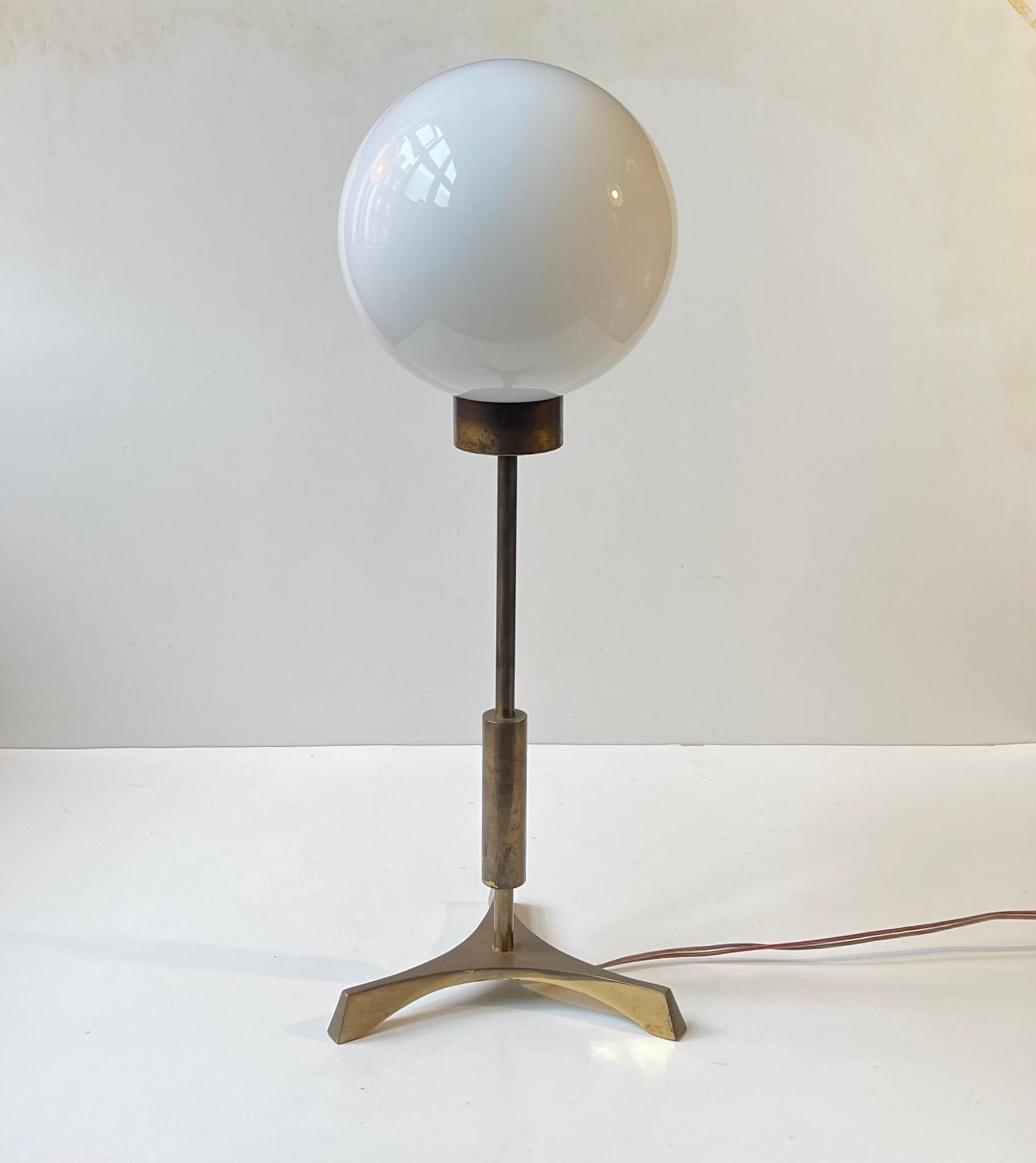 Rare lampe de table composée de laiton massif patiné et montée d'une sphère en verre opalin. D'un point de vue stylistique, il réunit tous les éléments nécessaires au design fonctionnaliste du milieu du siècle, avec un soupçon de brutalisme et d'art