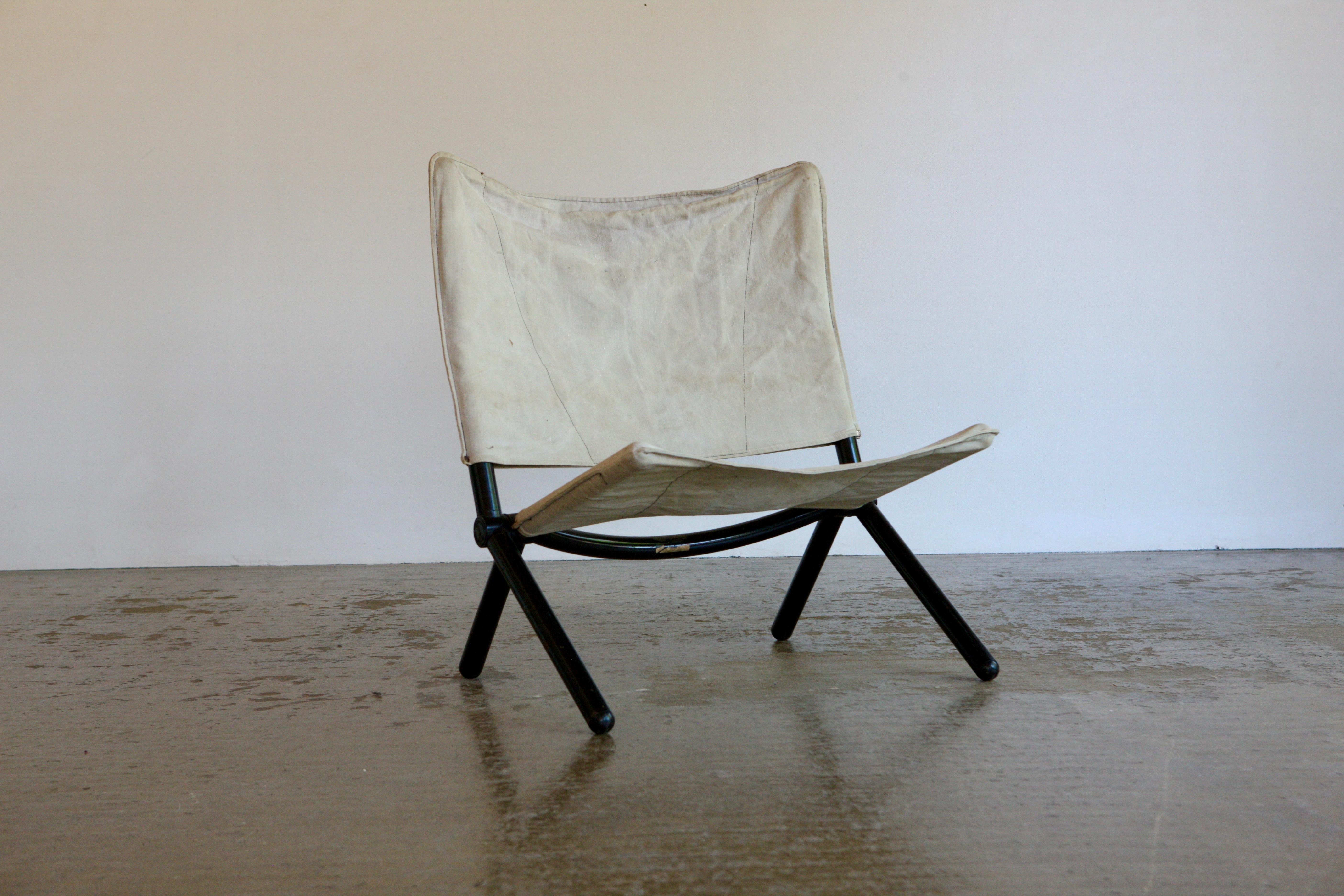 Silla de los años 70 con una amplia huella. La silla se pliega y tiene un grueso armazón tubular negro. En ella encaja el respaldo y el asiento de lona. Diseñado en la década de 1970 por T Ammannati y G P Vitelli para Brunati