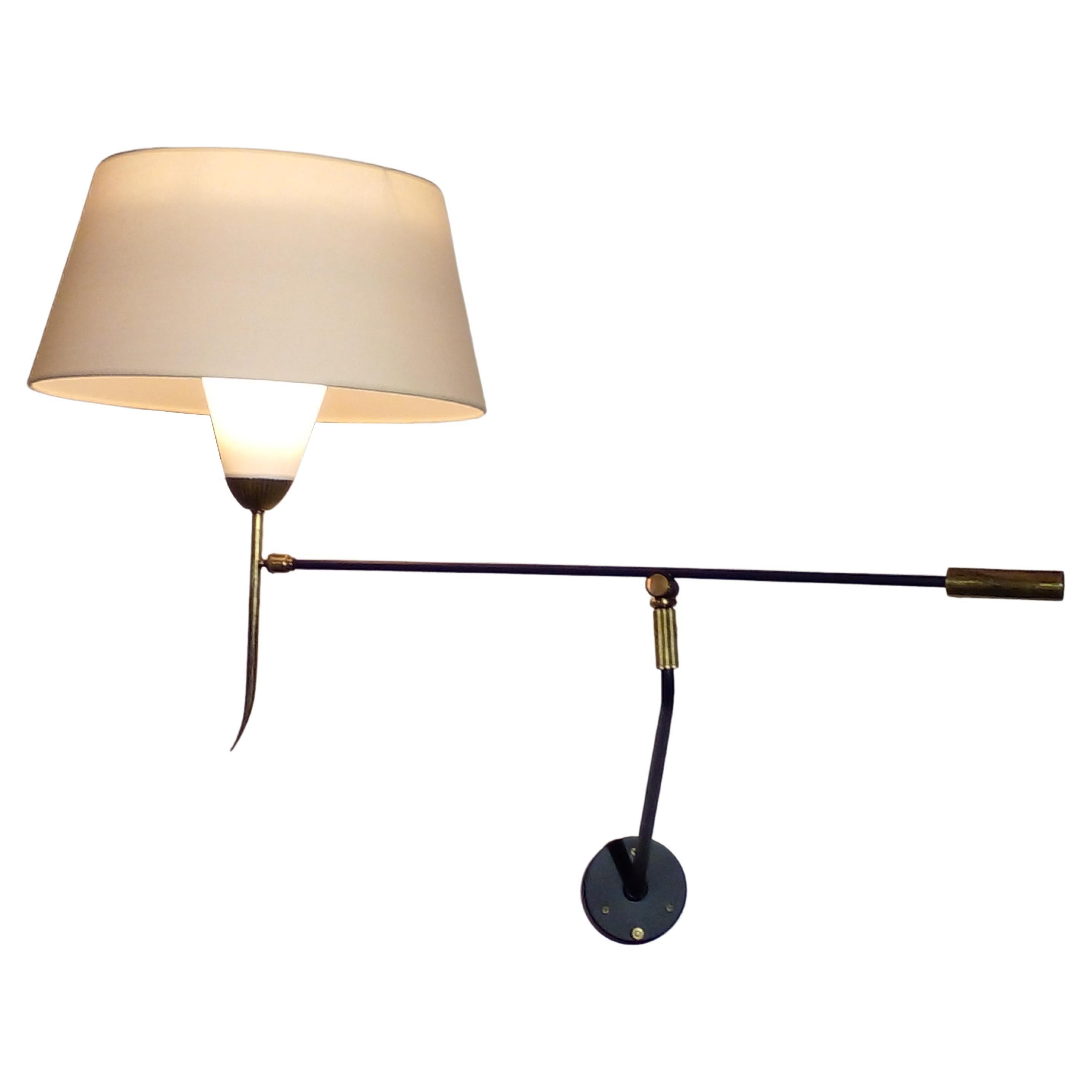 Foldable and adjustable wall light by Maison Lunel, France circa 1950.

This unusual wall lamp is composed of a swinging light arm with a double shade in cotton and celluloid mounted on a ball joint. This arm is itself fixed to an axis fixed to