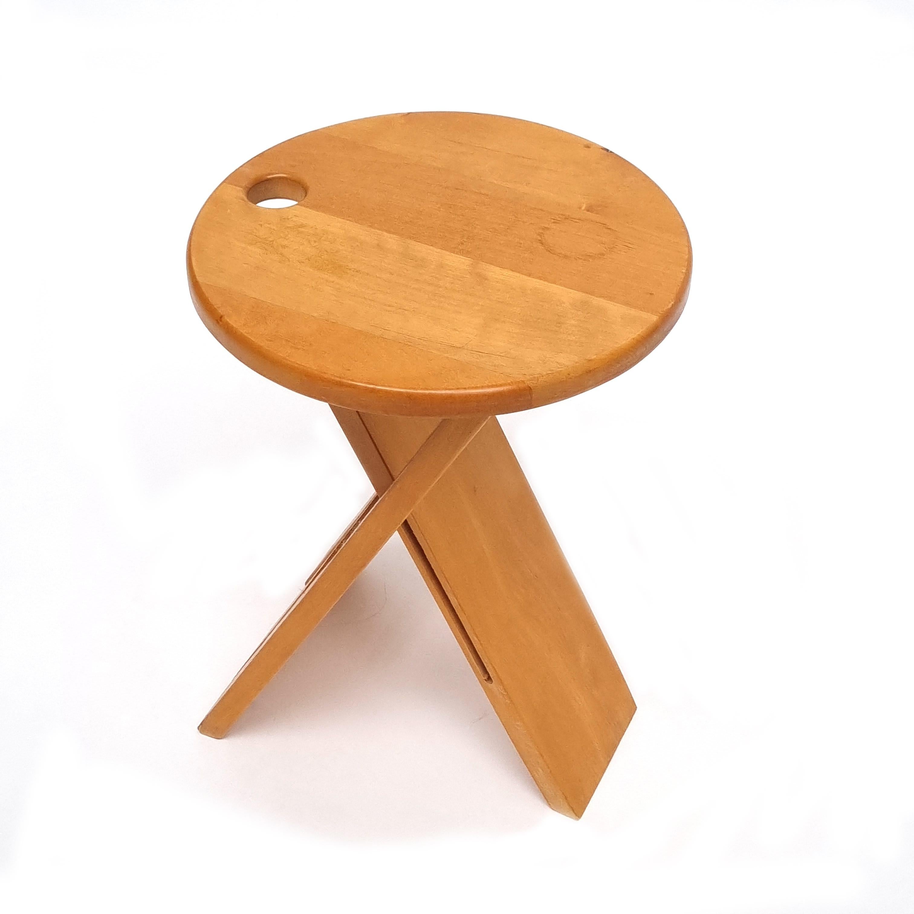 This pine stool from the 1980s has a Minimalist design. Designed by Adrian Reed for Princes Design Works Limited in London in 1984. It is foldable and has a hole allowing its suspension for optimal space saving. It is made of solid pine, foldable
