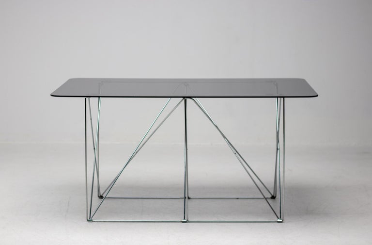 This elegant foldable chromed steel table with a floating smoked glass top was designed by Max Sauze, circa 1970, France. 

Max Sauze is a French industrial designer best known for his light fixtures. Made from intricately cut metal sheets and