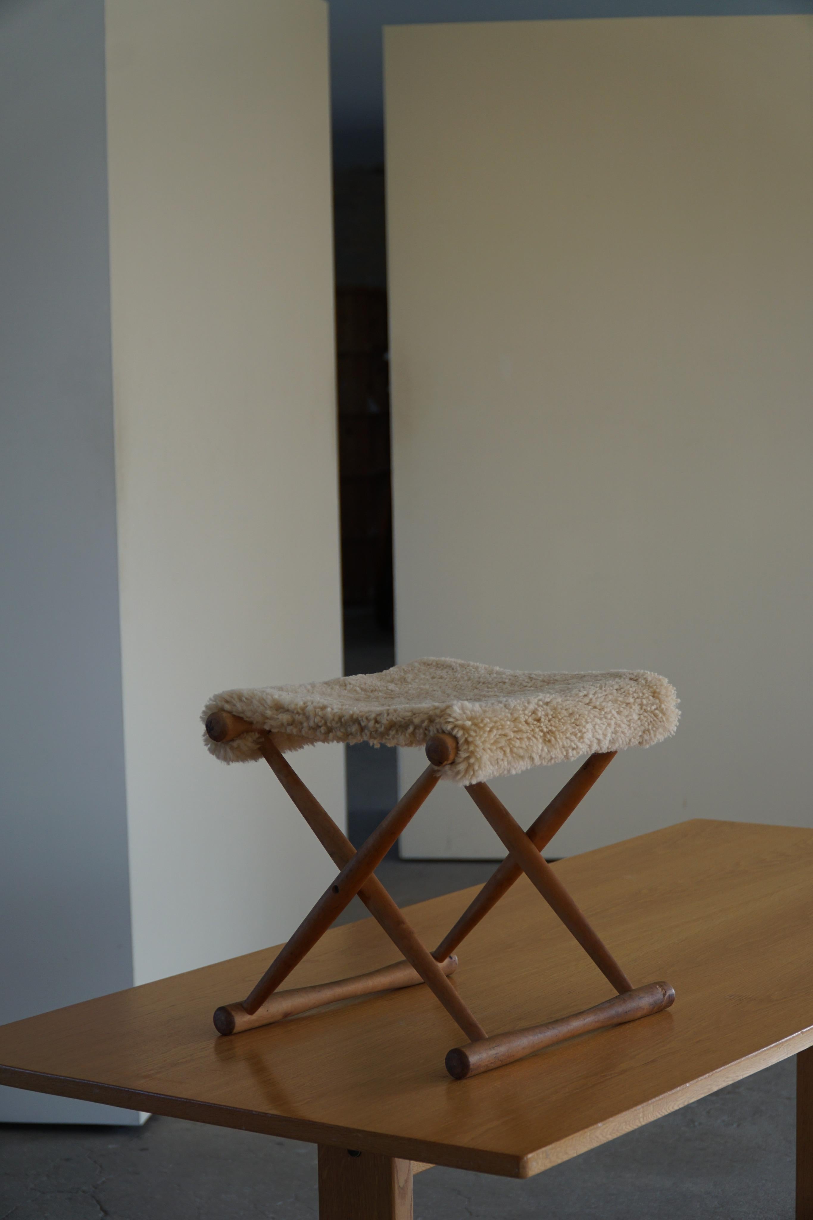 Foldable stool in solid beech, reupholstered seat in great quality shearling sheepskin. Made by an unknown Danish Cabinetmaker in the 1950s. 

A great object for the Scandinavian interior home. The overall impression is really good.

With a