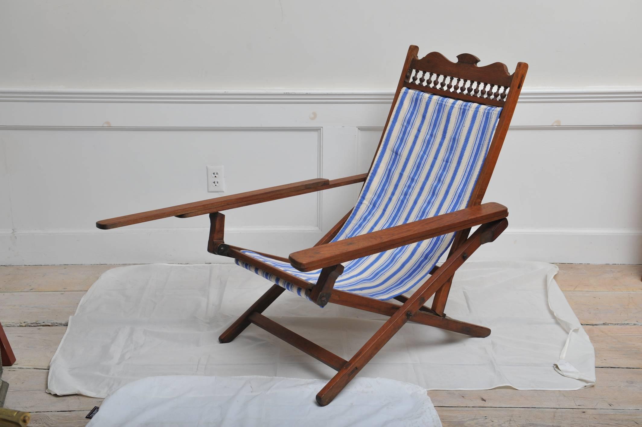 British Campaign sling-back teak plantation chair from the 1940s (fabric replaced). It folds, adjusts (4 settings) and the arm rests pull forward to create leg rests. Brass hardware and turned dowel back and detachable pillow. Fabric width is 19
