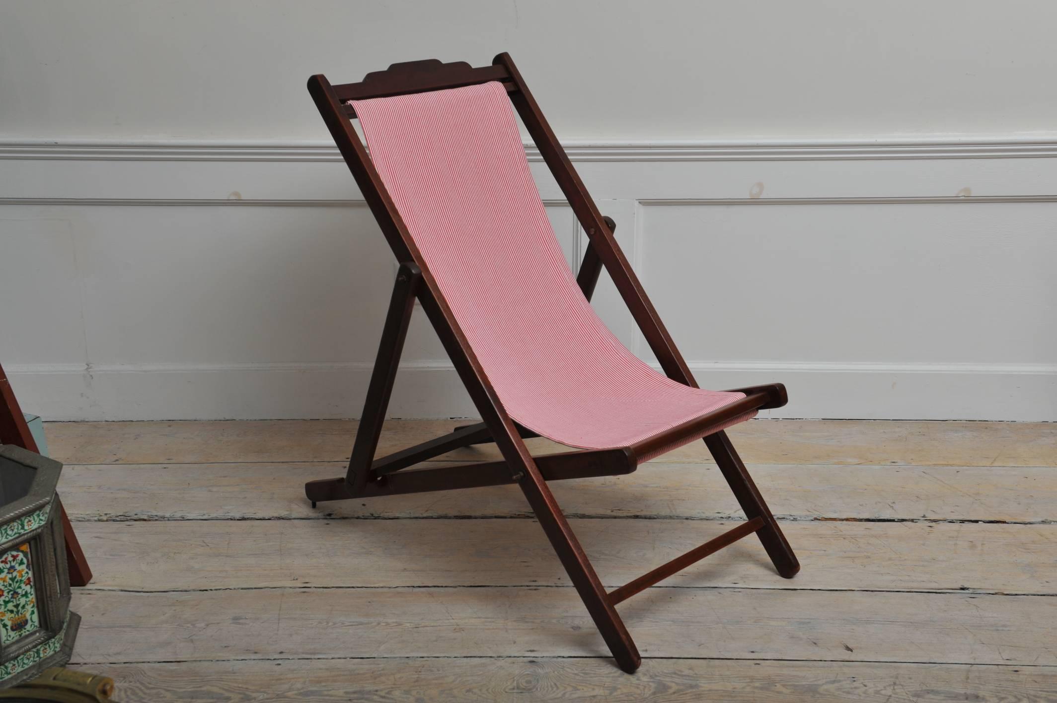 A folding and adjustable (three settings) teak lounge chair from the 1940s with a red and white striped sling seat. The canvas has been replaced and we include a matching, detachable pillow. 1940s, British Campaign. There is a very easy mechanism